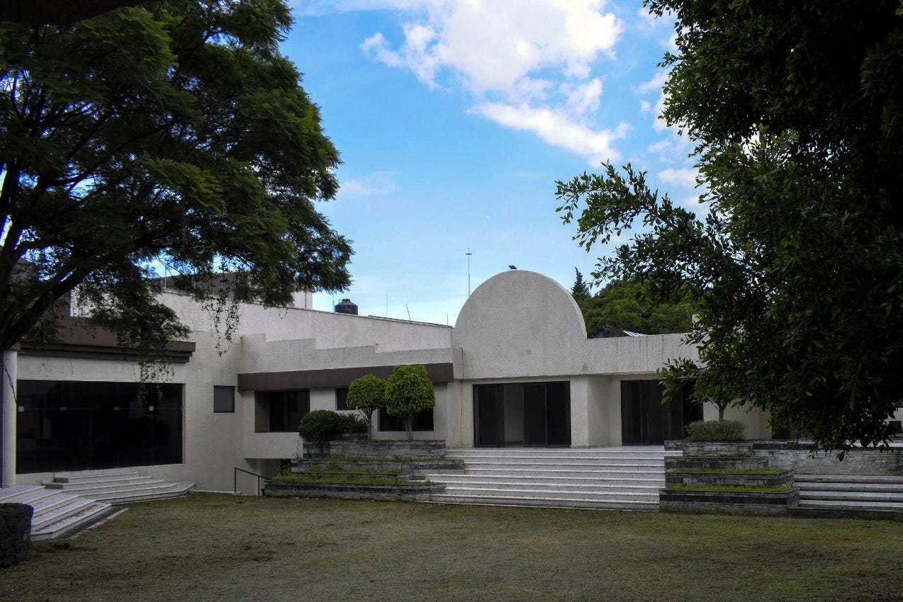 A large single-story house is seen from the front driveway.