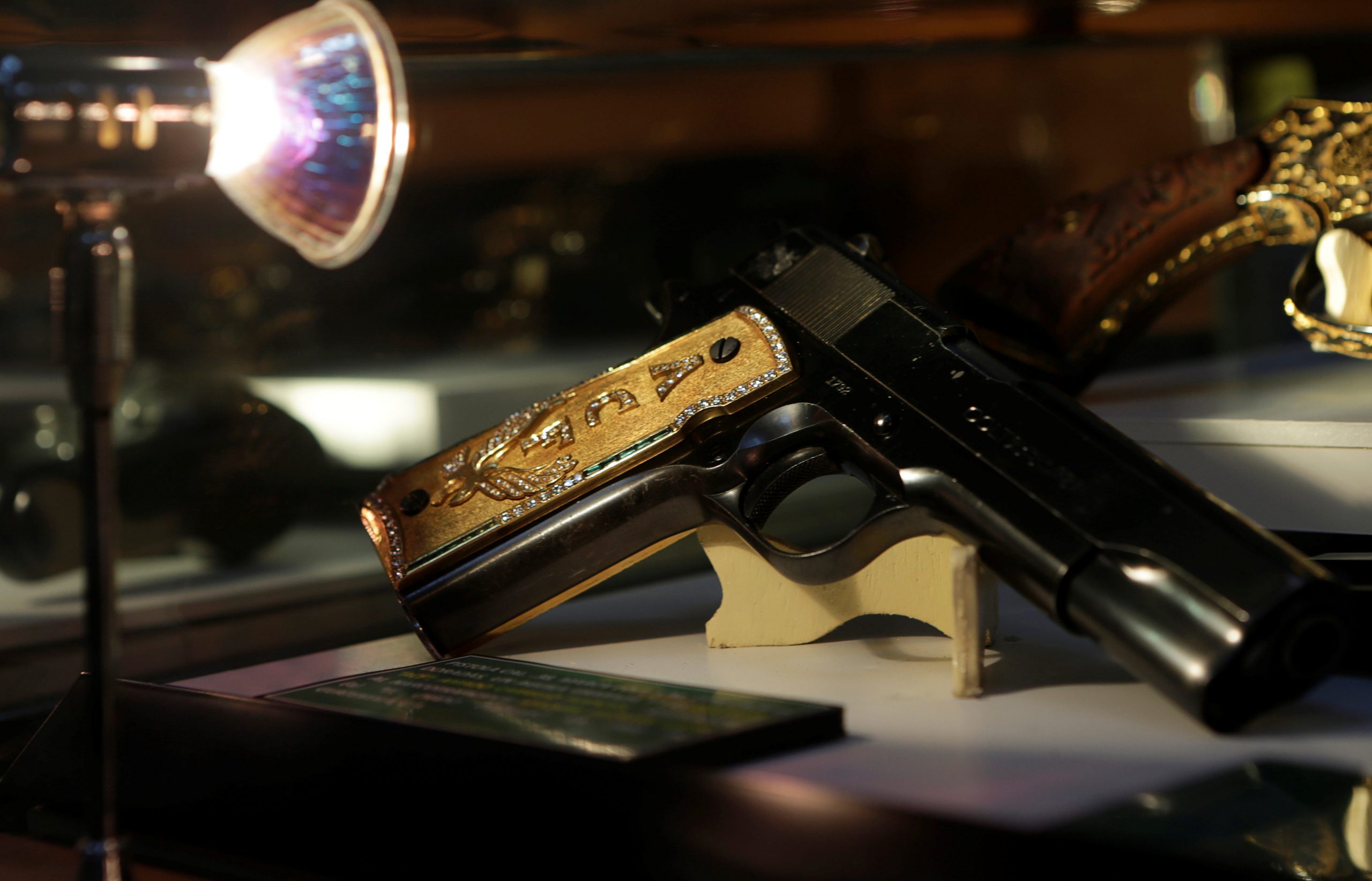 A gun is seen displayed under the glare of a light.