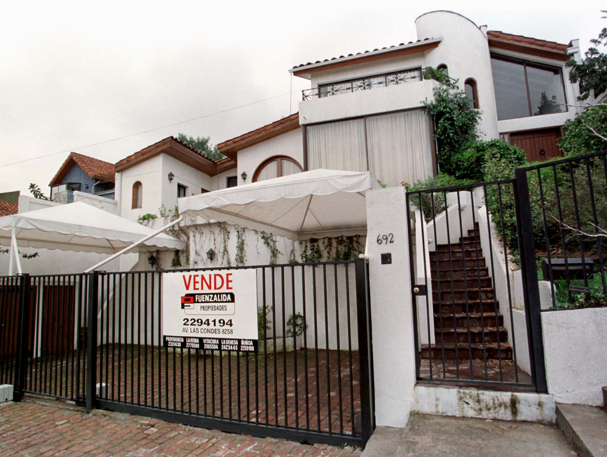 The facade of a white and brown house with steps leading up to it.