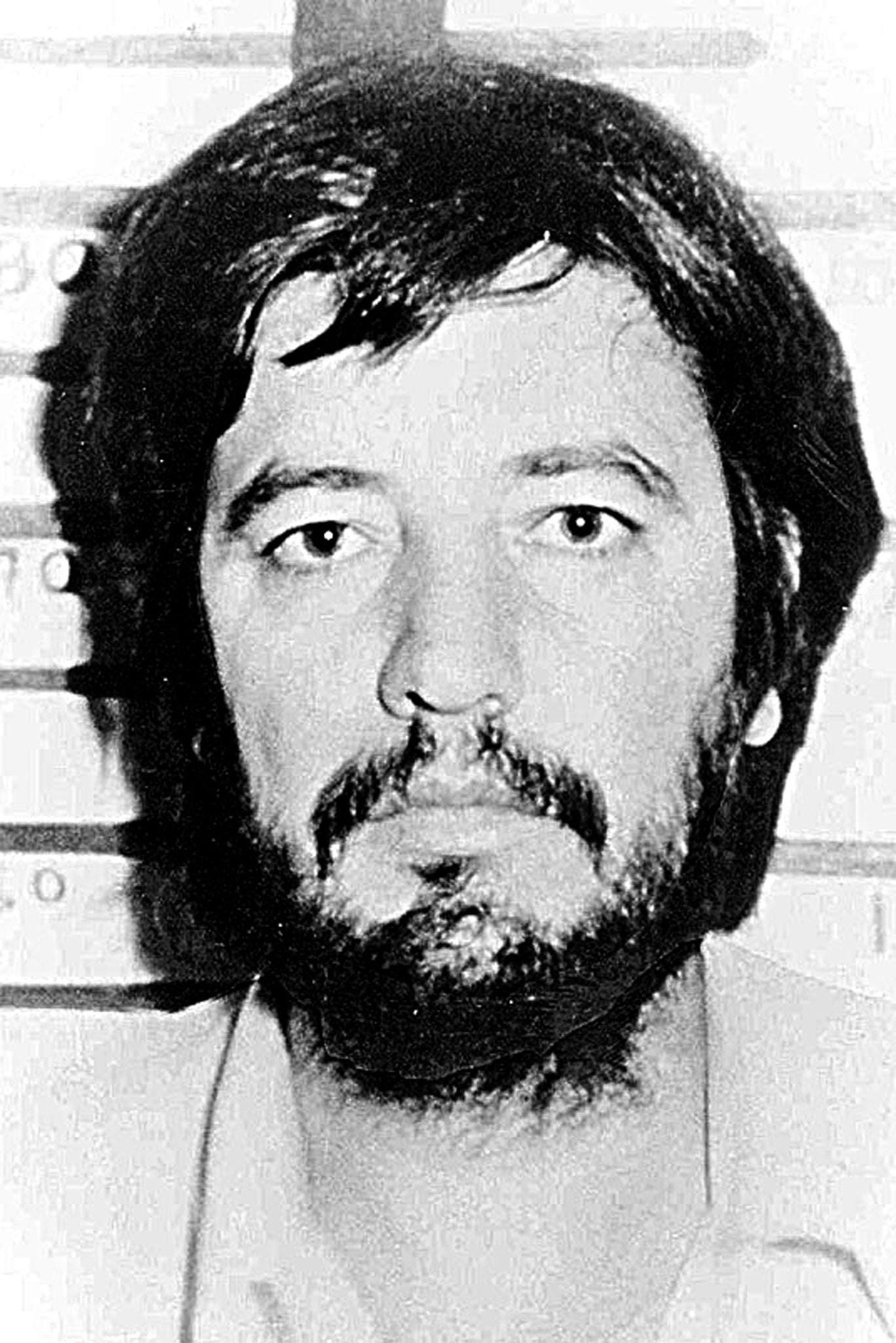 A mugshot of an unsmiling man with a beard.