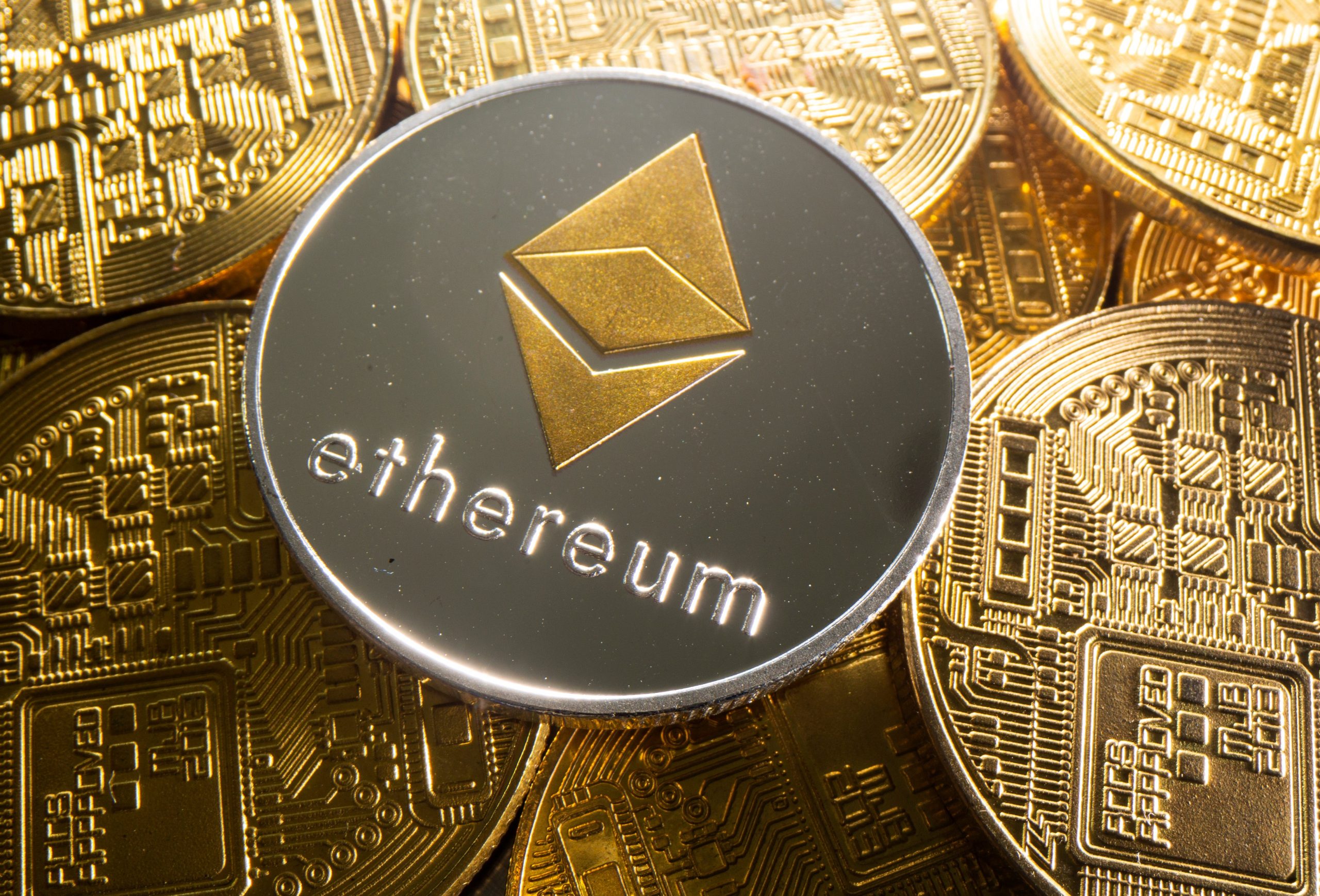 A coin withe an Ethereum logo on top of other gold coins