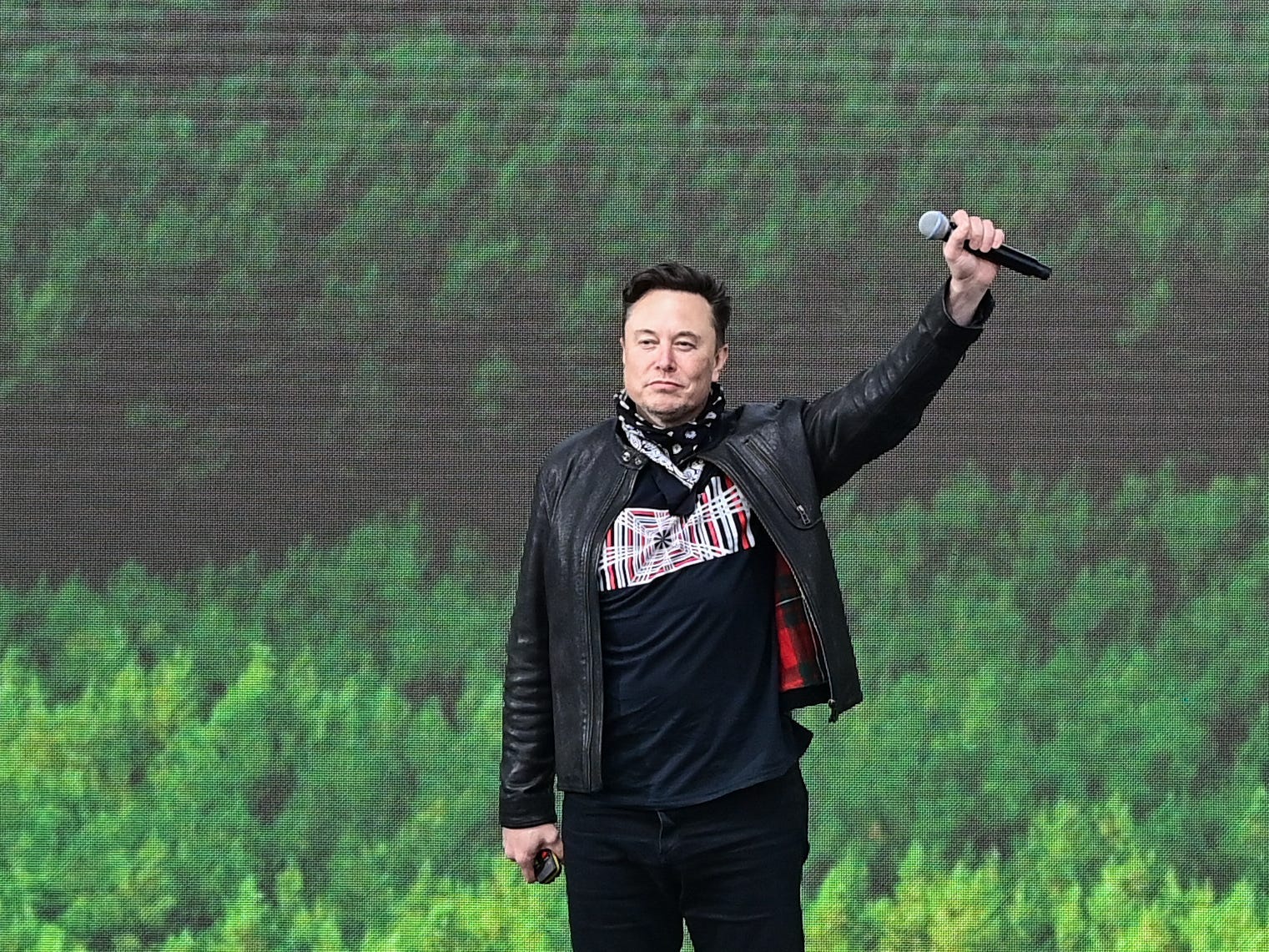Tesla CEO Elon Musk raises a mic over his head in front of a crowd in Germany