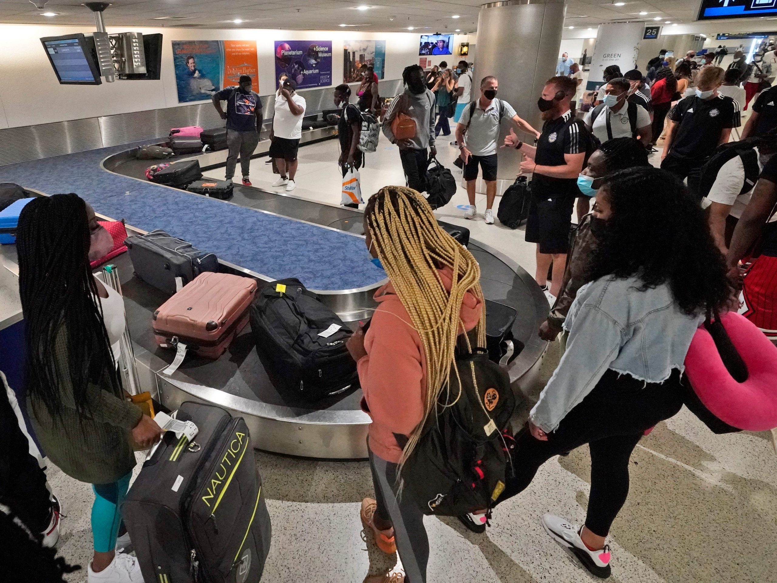 Travelers wait for their luggage at a baggage carousel, Friday, May 28, 2021, at Miami International Airport in Miami.