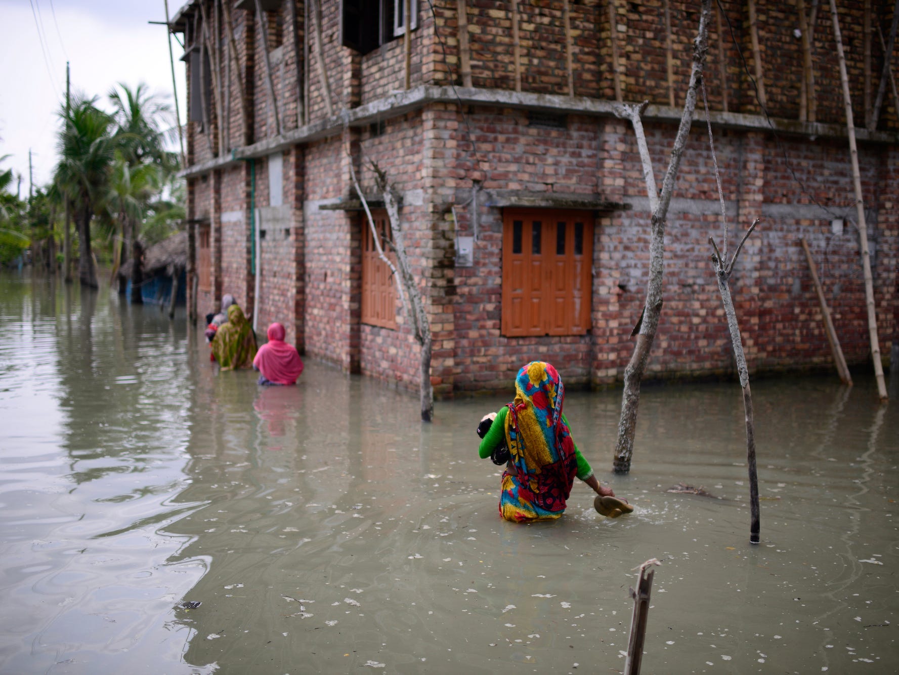 Villagers wade through waist-deep waters to reach their homes in Pratap Nagar that lies in the Shyamnagar region, in Satkhira, Bangladesh on Oct. 5, 2021