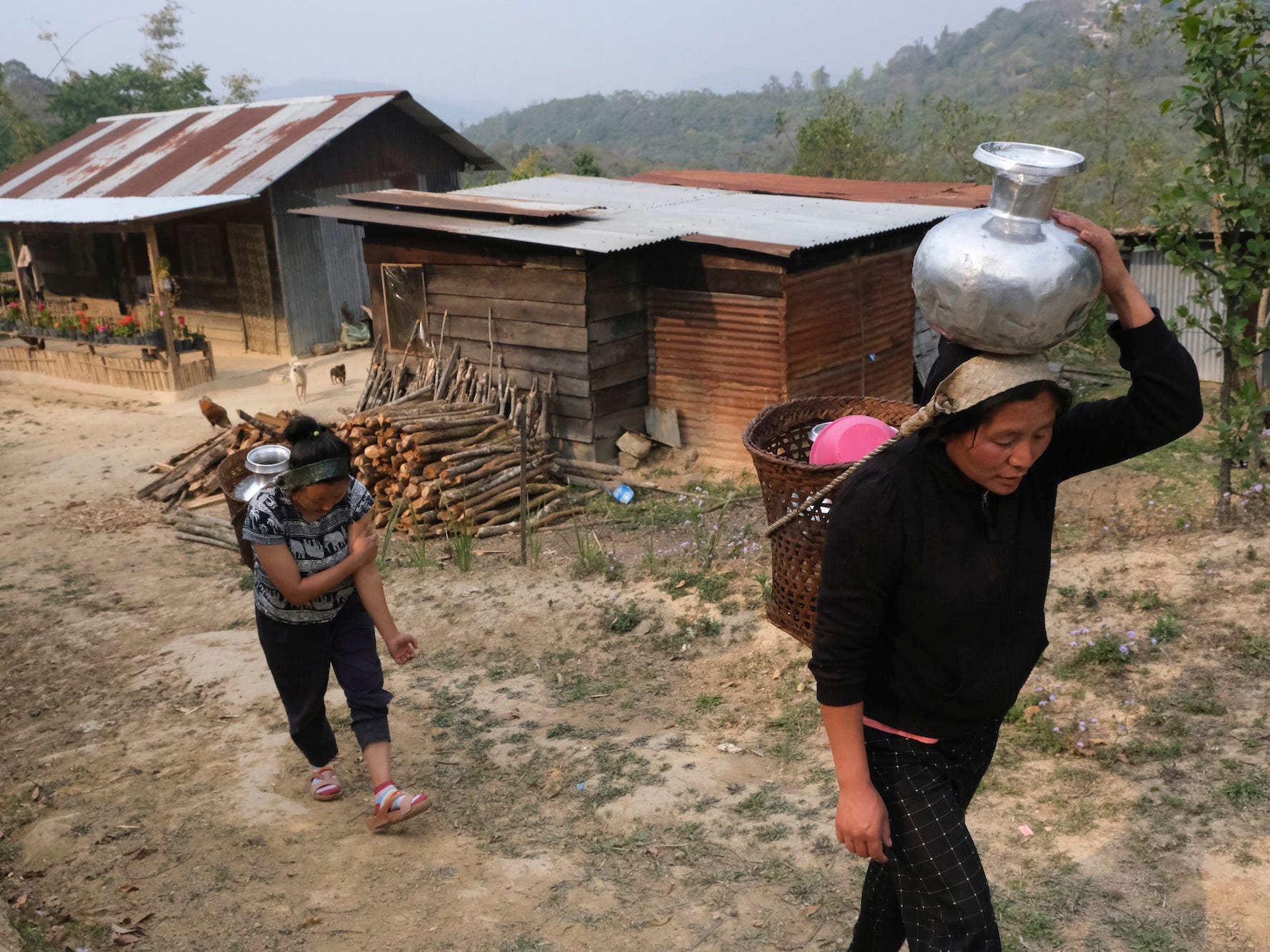 Tonchuiwon Tinphei, 34, right, and her sister-in-law Chirmi carry water in baskets and walk home on the eve of World Water Day in Shangshak village, in the northeastern Indian state of Manipur, Saturday, March 21, 2020.