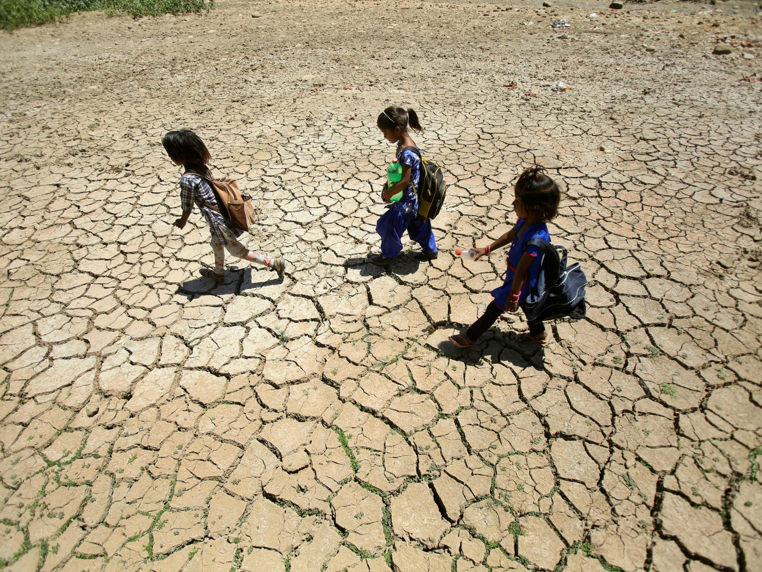 In this Thursday, May 30, 2019, file photo, children returning from school walk through a dried pond on a hot summer day on the outskirts of Jammu, India. Many parts of India are experiencing extreme heat conditions.