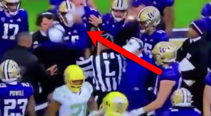 Washington football coach Jimmy Lake strikes a player on sideline during a game.