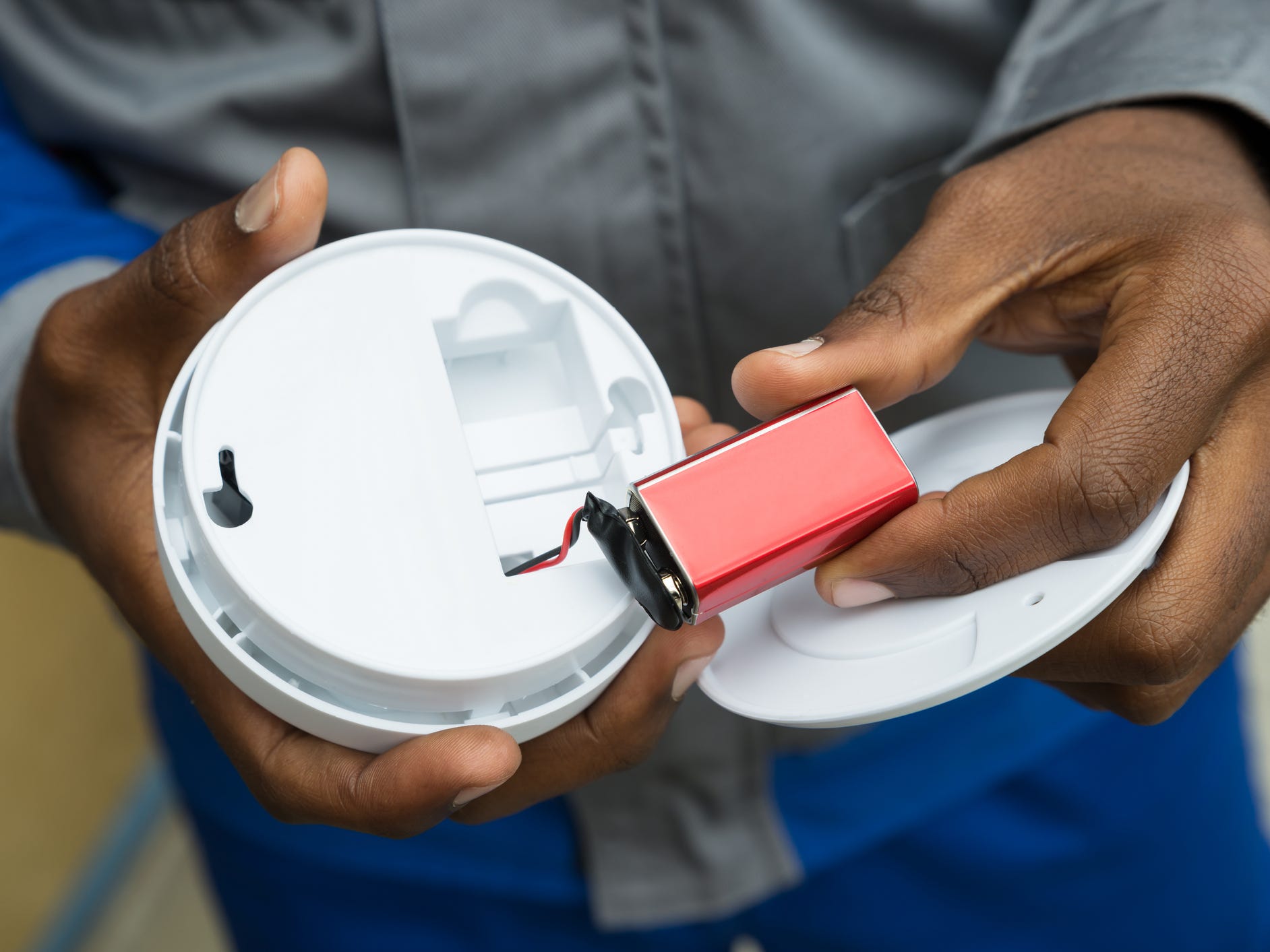 An electrician removing a battery from a smoke detector.