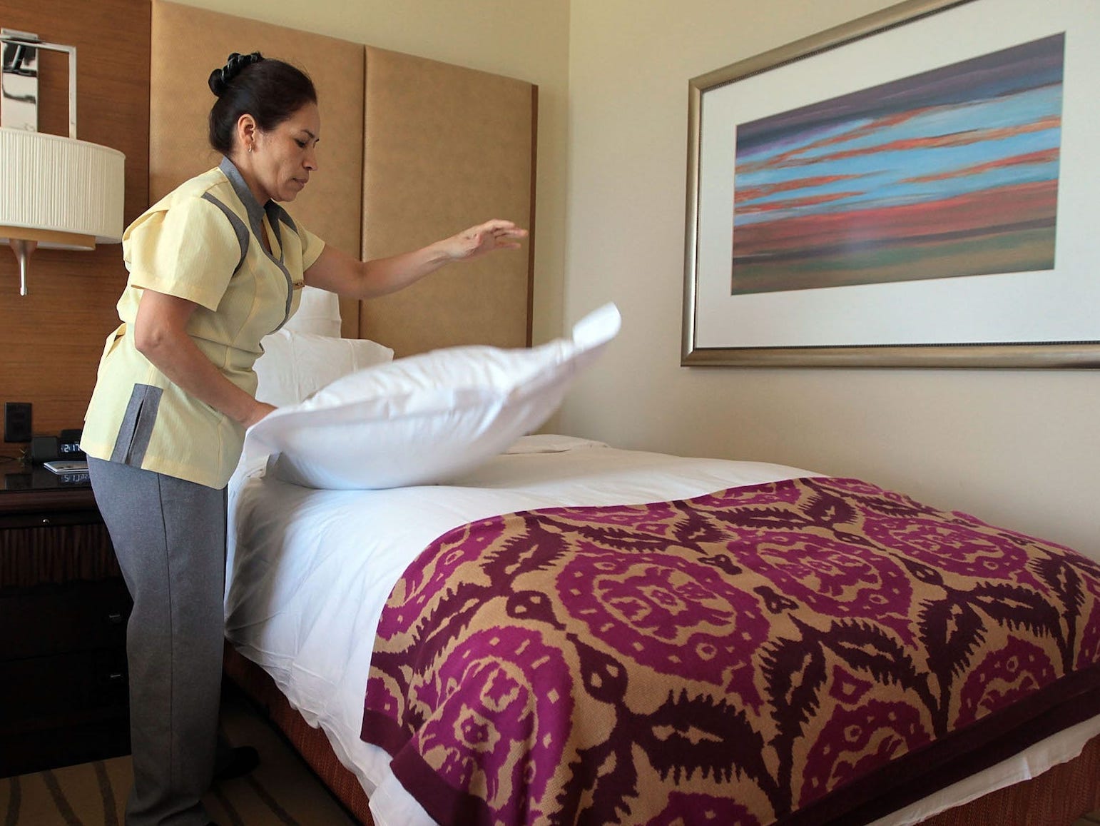 A hotel worker is making a bed.