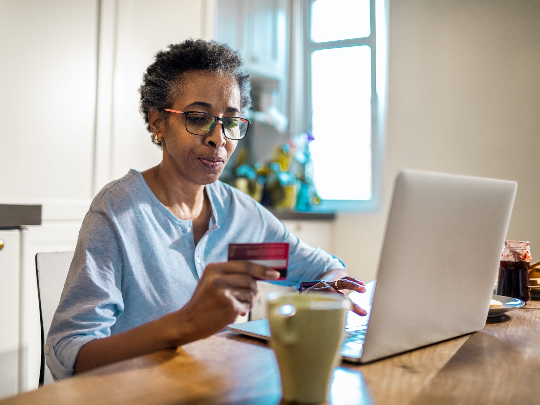 senior woman shopping online on laptop holding credit card