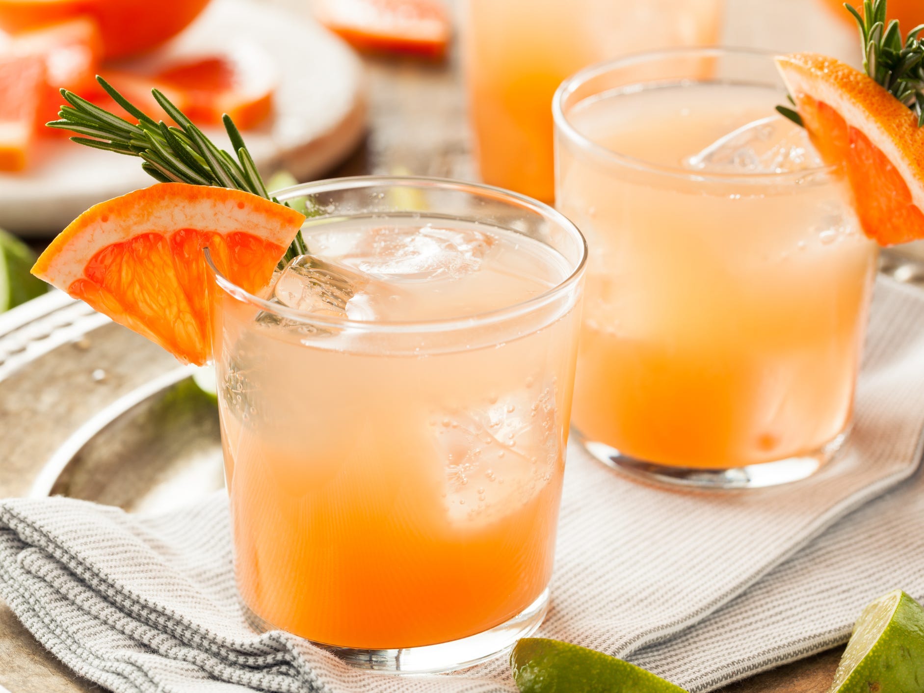 Two paloma cocktails on a silver tray garnished with grapefruit and rosemary