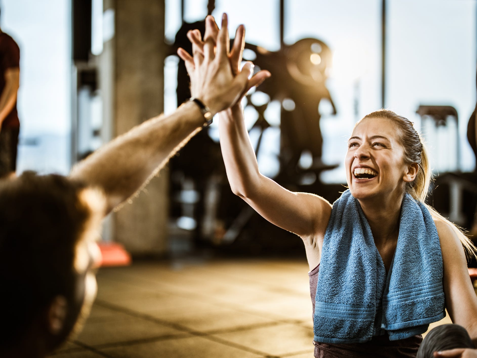 A smiling athlete at the gym giving a high five after a happy workout; enjoying exercise