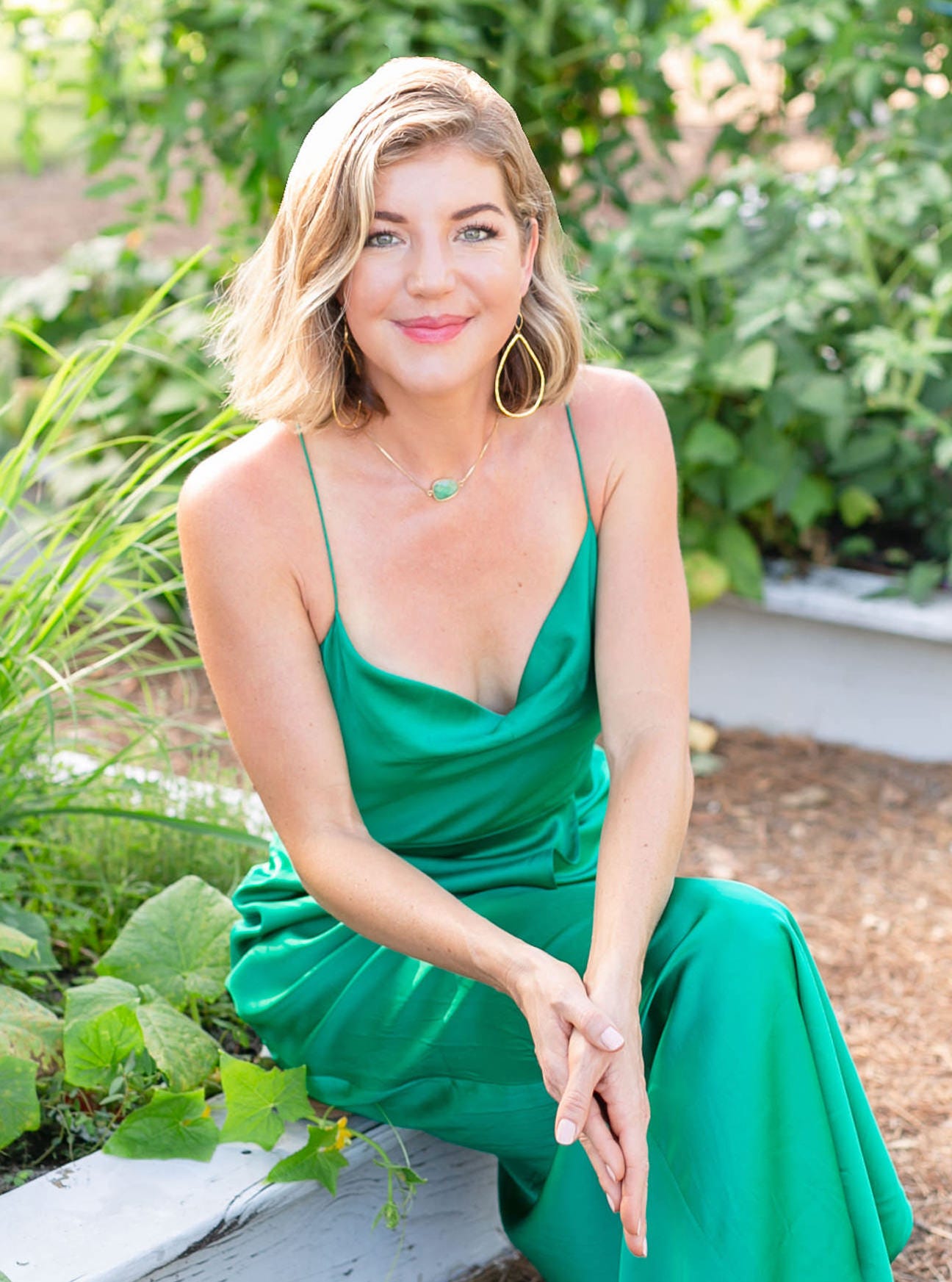 business coach Jessica Caver Lindholm wears a green dress and sits in a garden