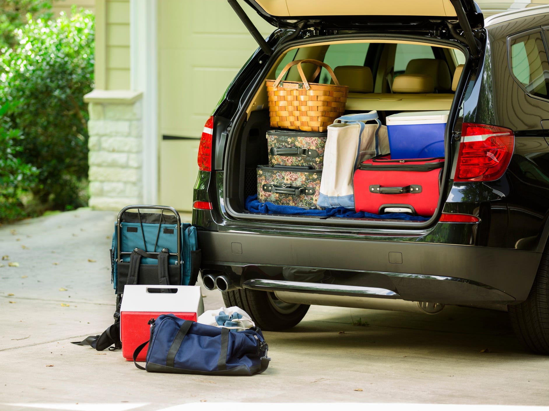 A hatchback car trunk full of suitcases and coolers