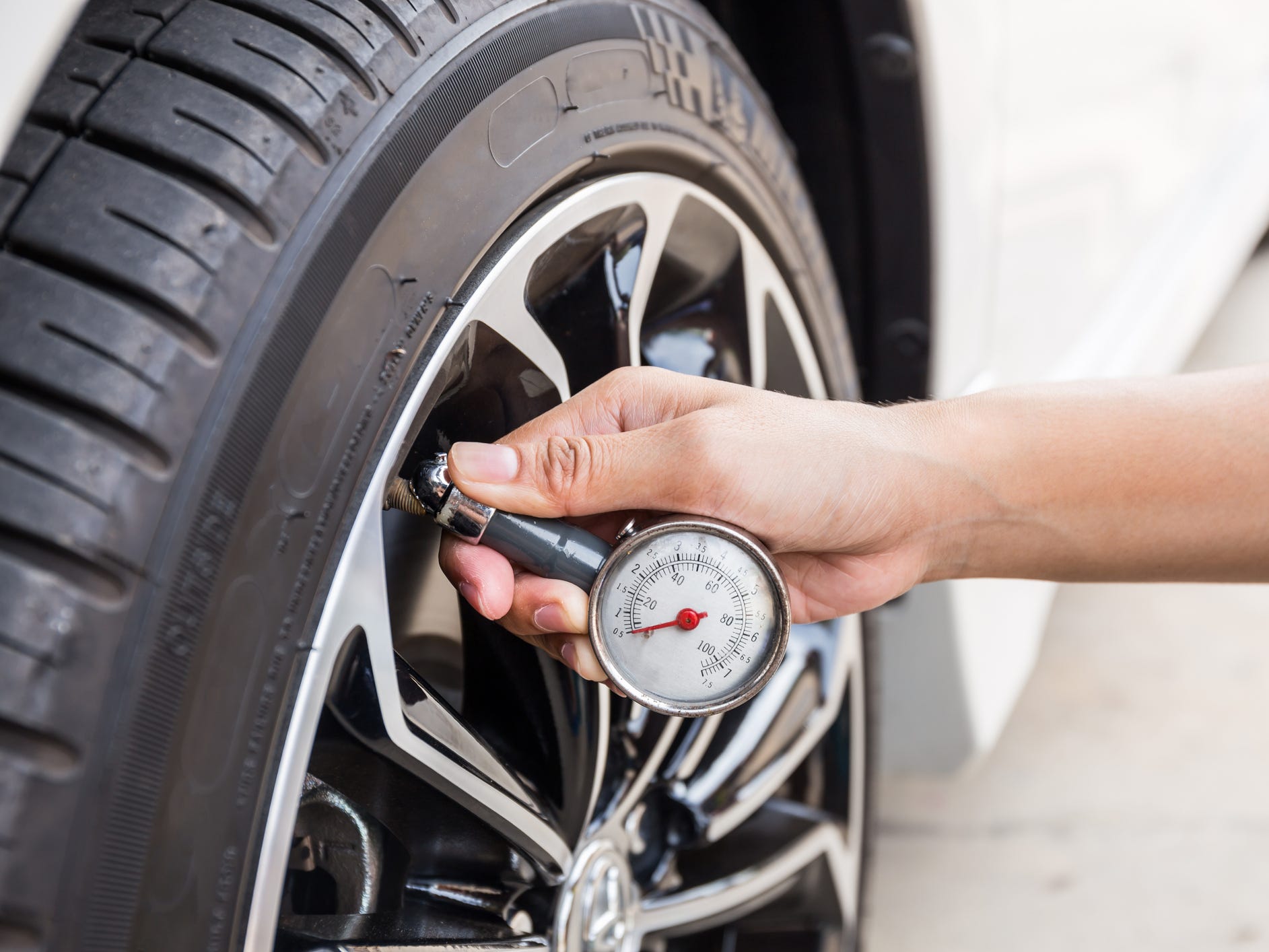 A hand using a gauge to check tire pressure