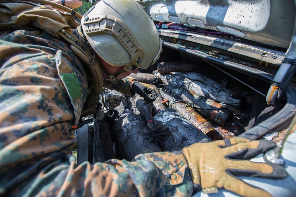 Een marinier die explosieven opruimt, bekijkt een nagemaakt explosief in een voertuig tijdens een training. Foto: US Marine Corps