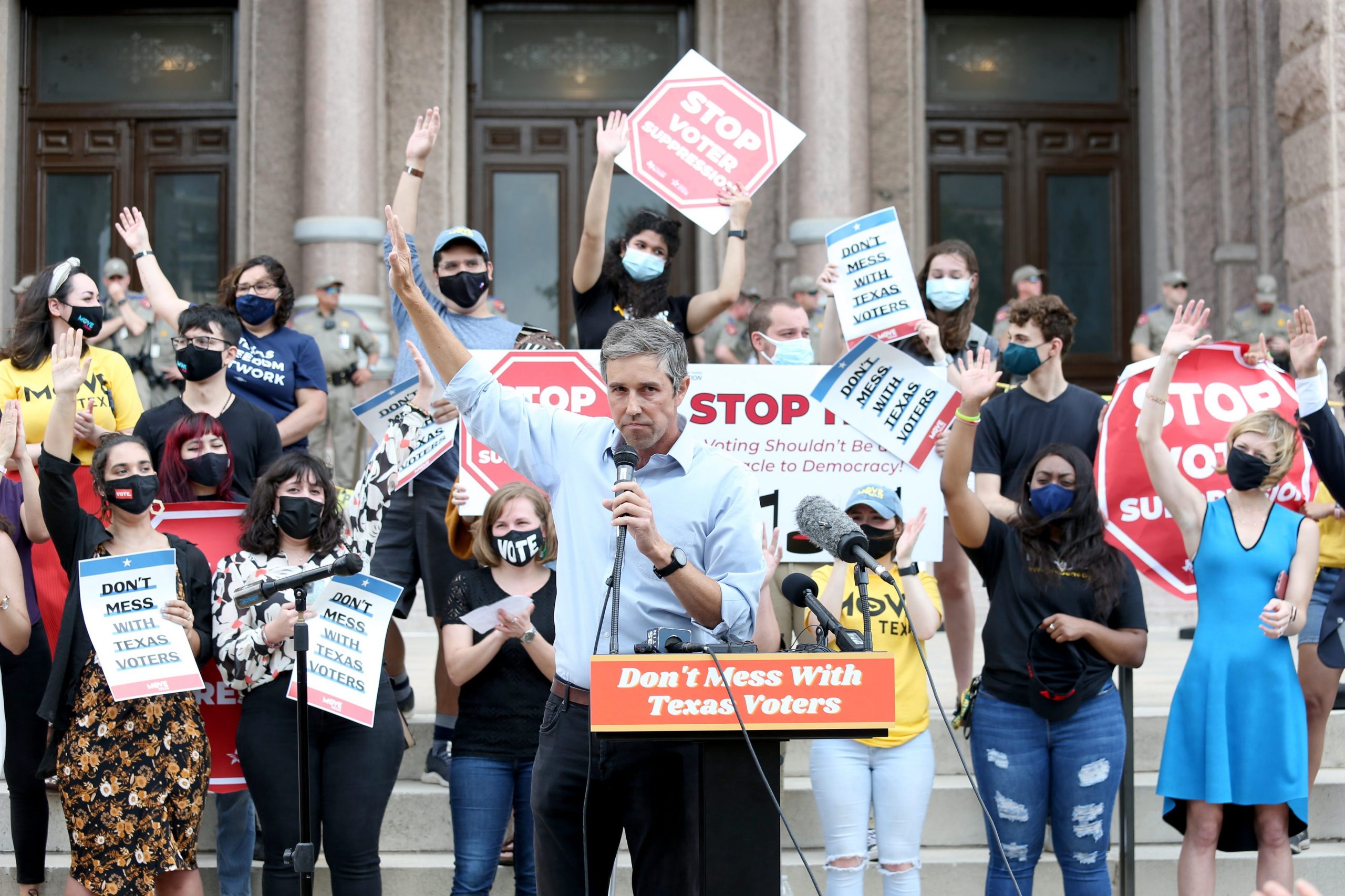 Supporters with hands raised and signs in support of voting rights cheer behind former US representative Beto O'Rourke.