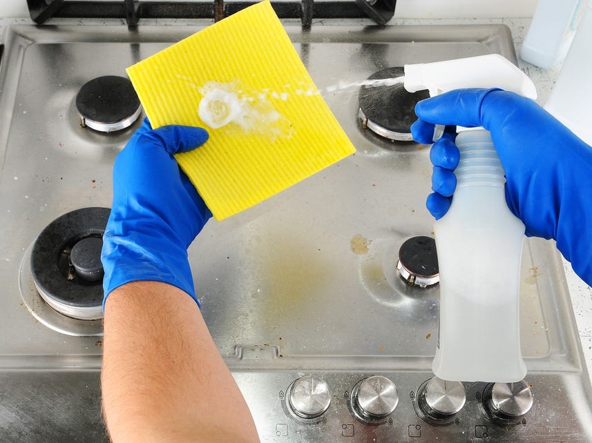 Cleaner sprays liquid on a cloth for cleaning the kitchen.