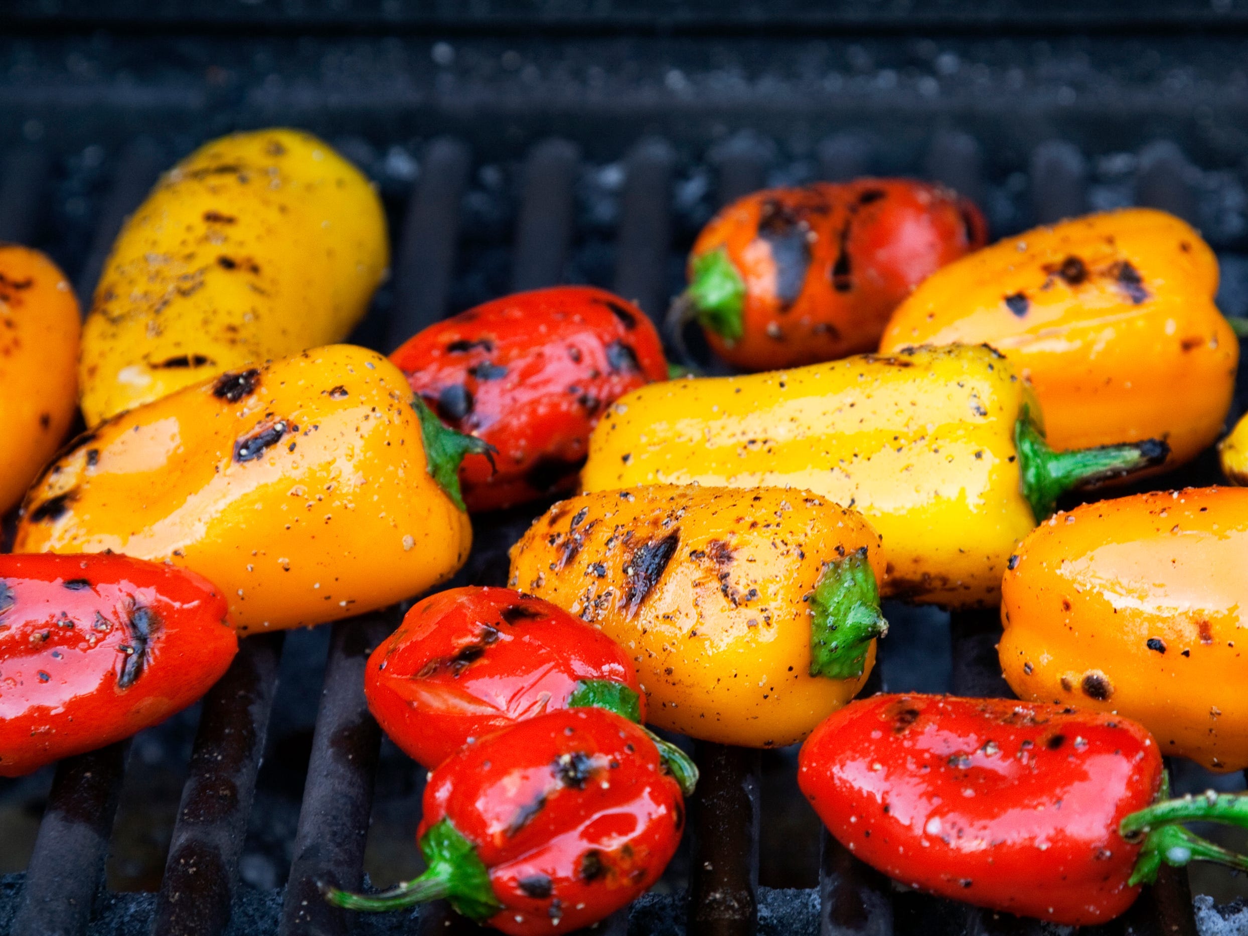 Small red and yellow peppers on a grill