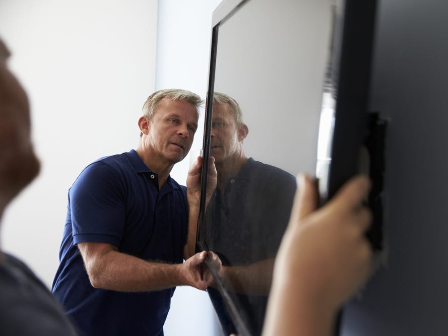 Two men fitting a flat screen TV to a wall.