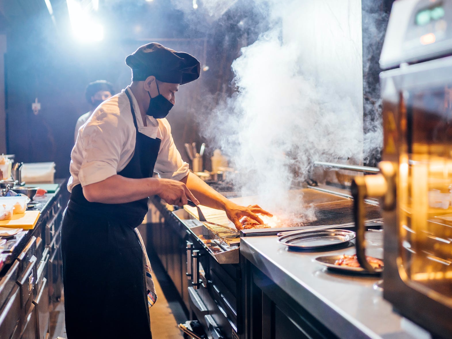 chef cooking in a restaurant kitchen and wearing a mask