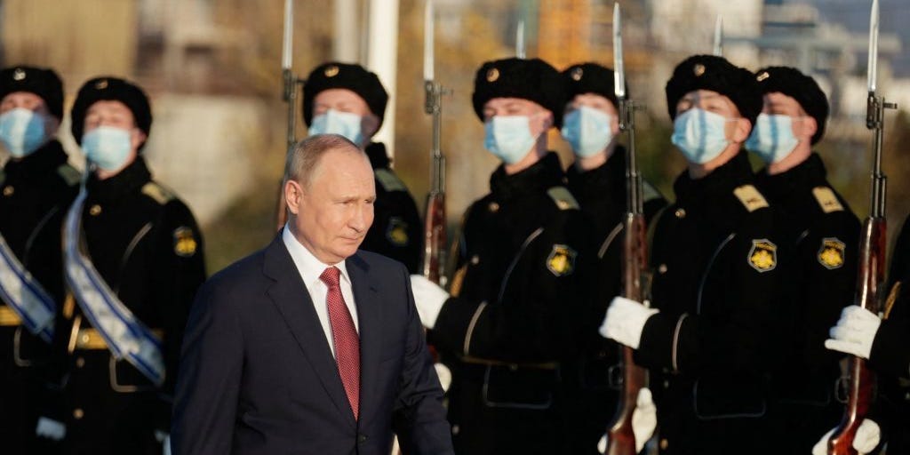Russian President Vladimir Putin walks past military personnel during a ceremonial event.