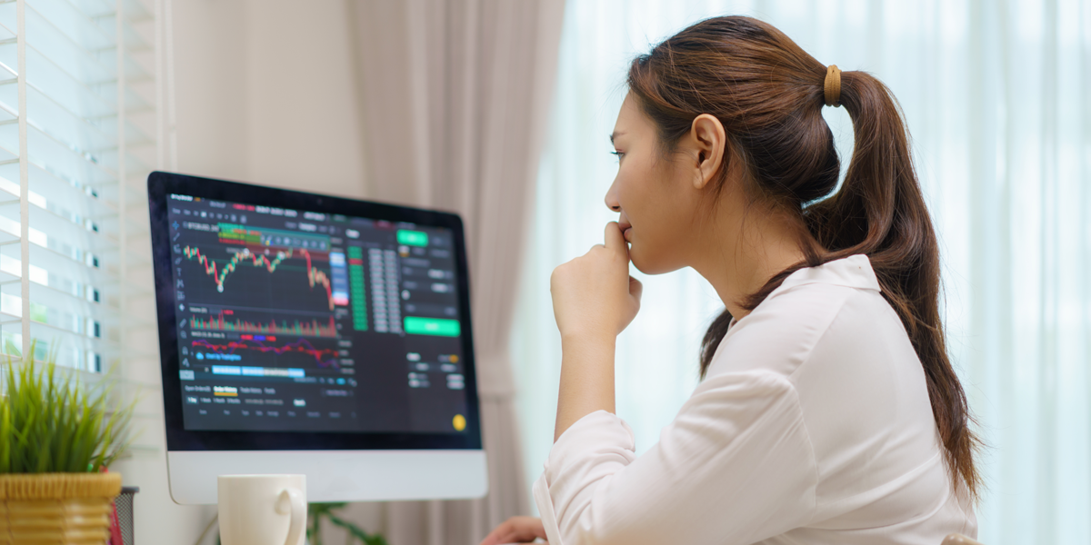 A photo of a woman studying stock charts on a computer screen.