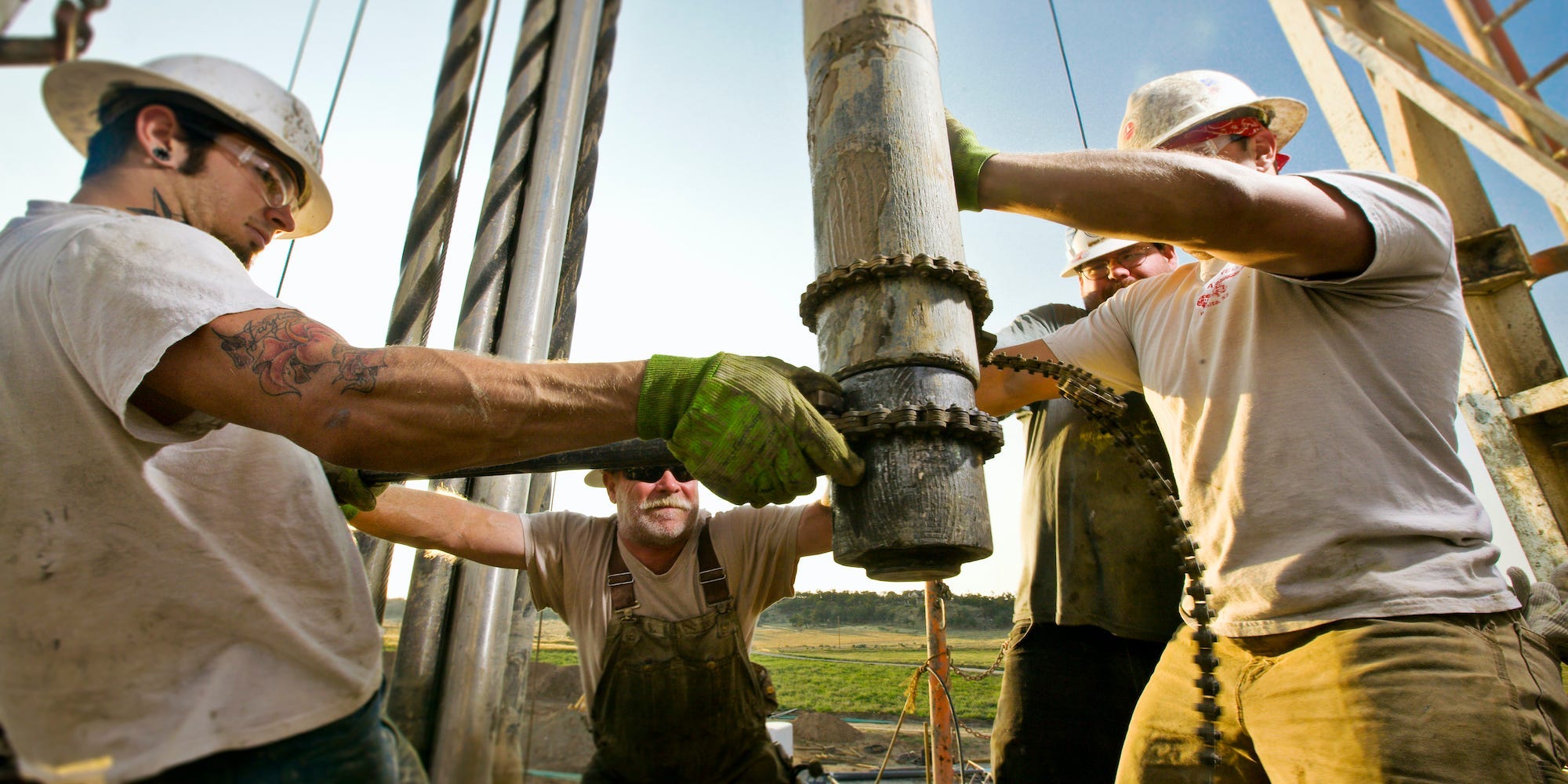 Oil workers using chain to position drill on drilling platform