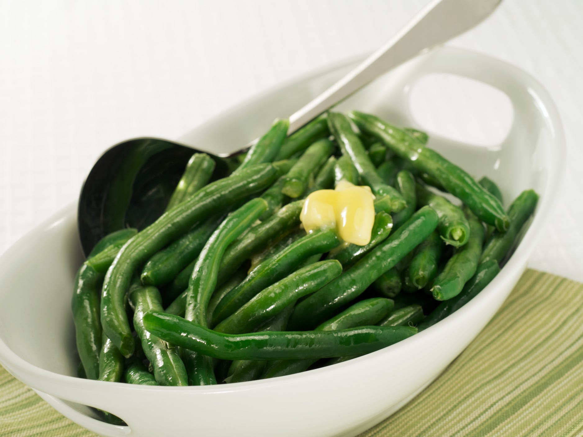 A bowl of green beans topped with a nob of melting butter