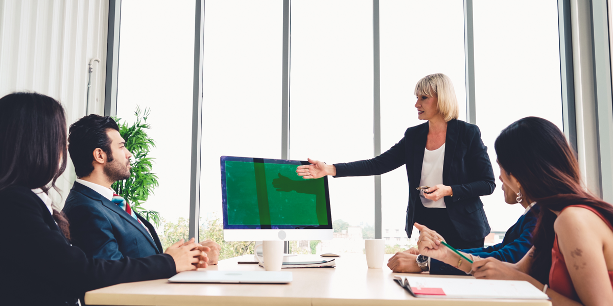 A photo of business people looking at a computer screen in a conference room.