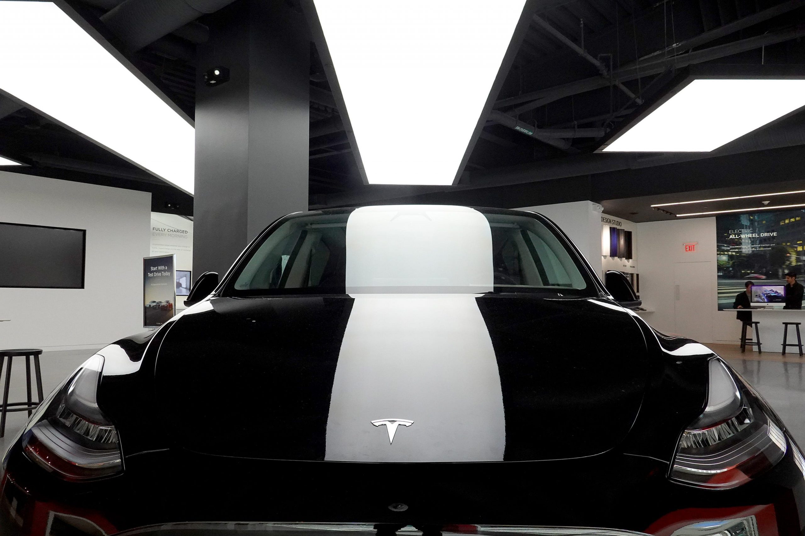 A black Tesla Model Y electric vehicle under a bright light in a showroom