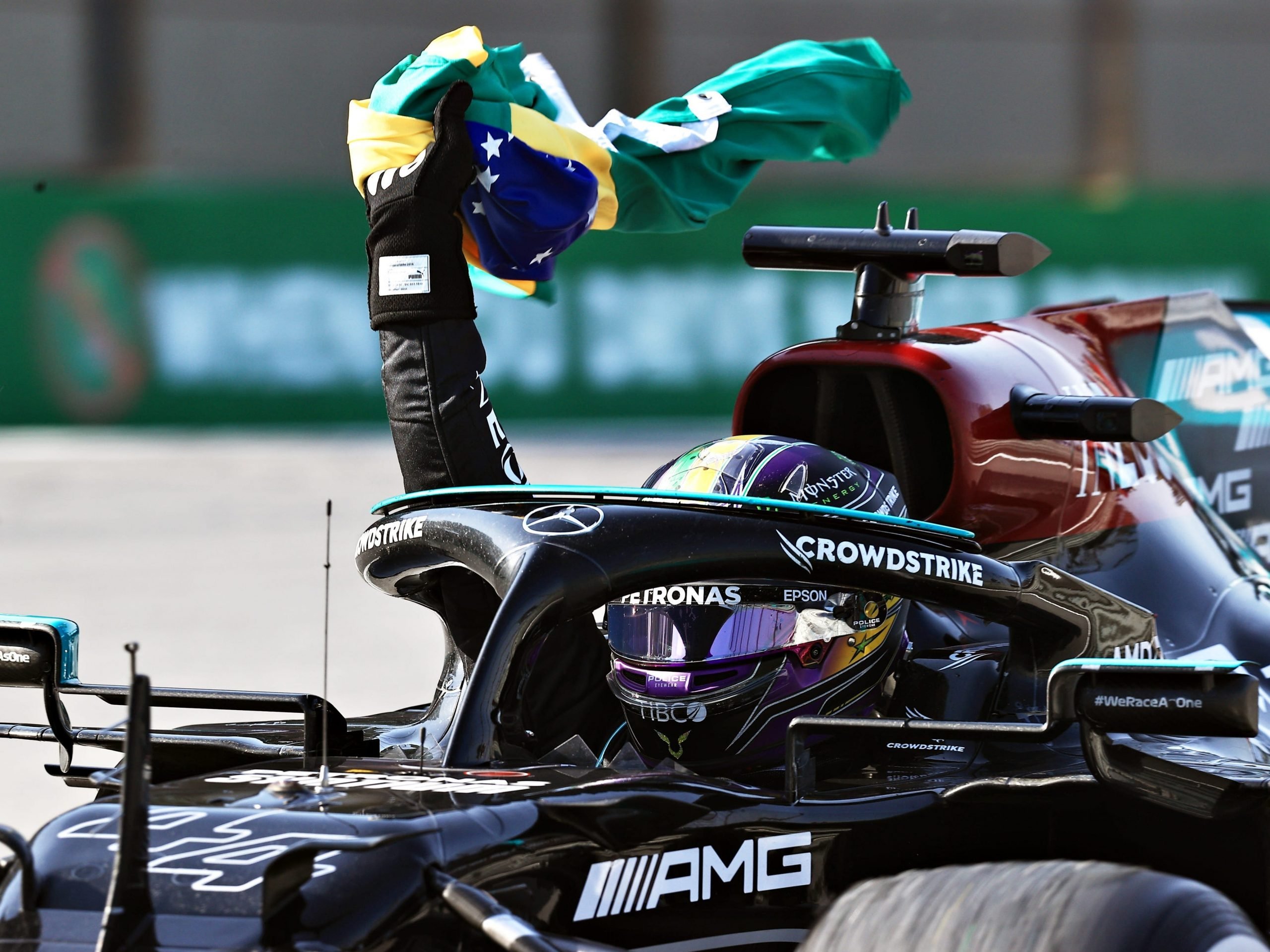 Lewis Hamilton waves a Brazilian flag after winning the Grand Prix.