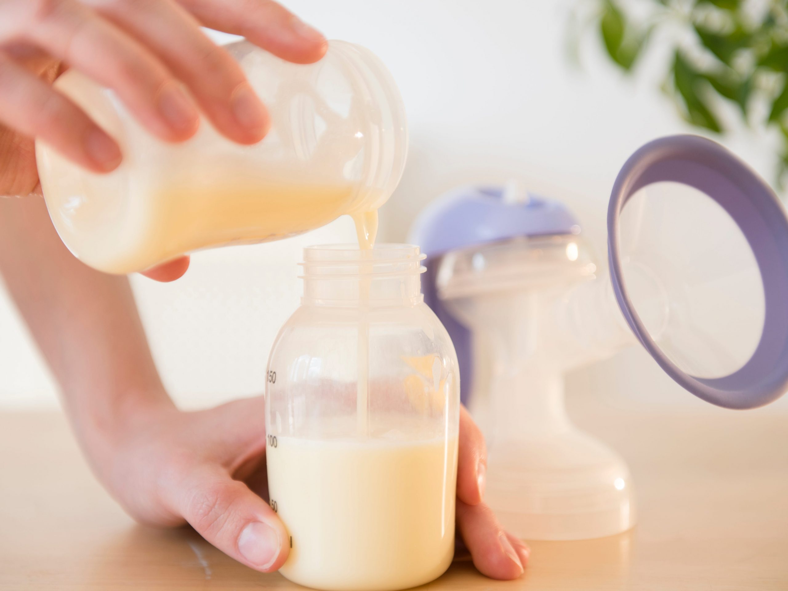 woman pouring breast milk into bottle