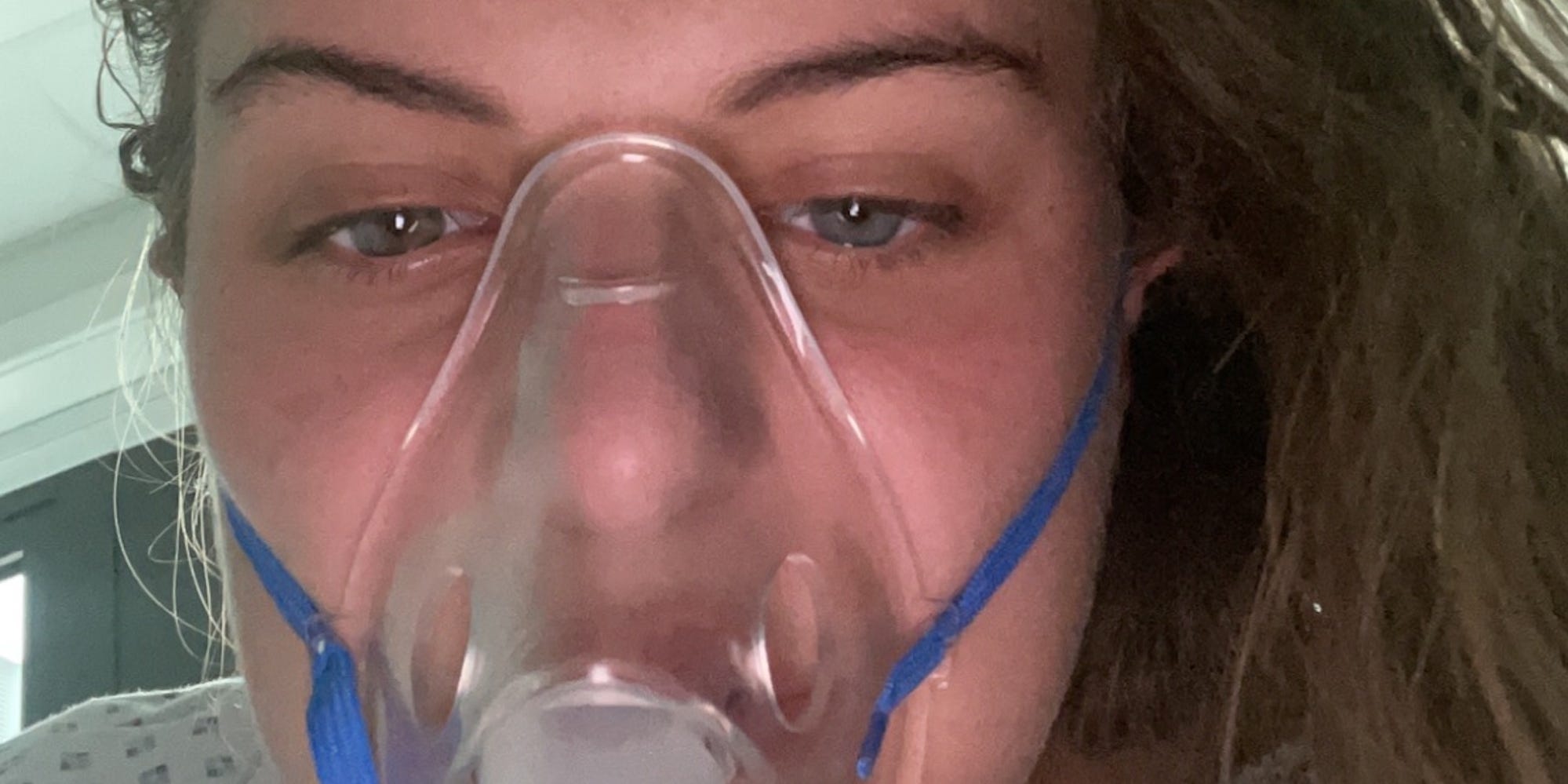 A selfie of Maisy Evans wearing a hospital gown and a mask to help breathing.