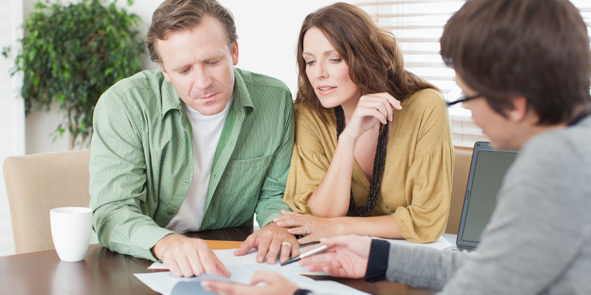 A couple meeting with a financial advisor and looking over papers.