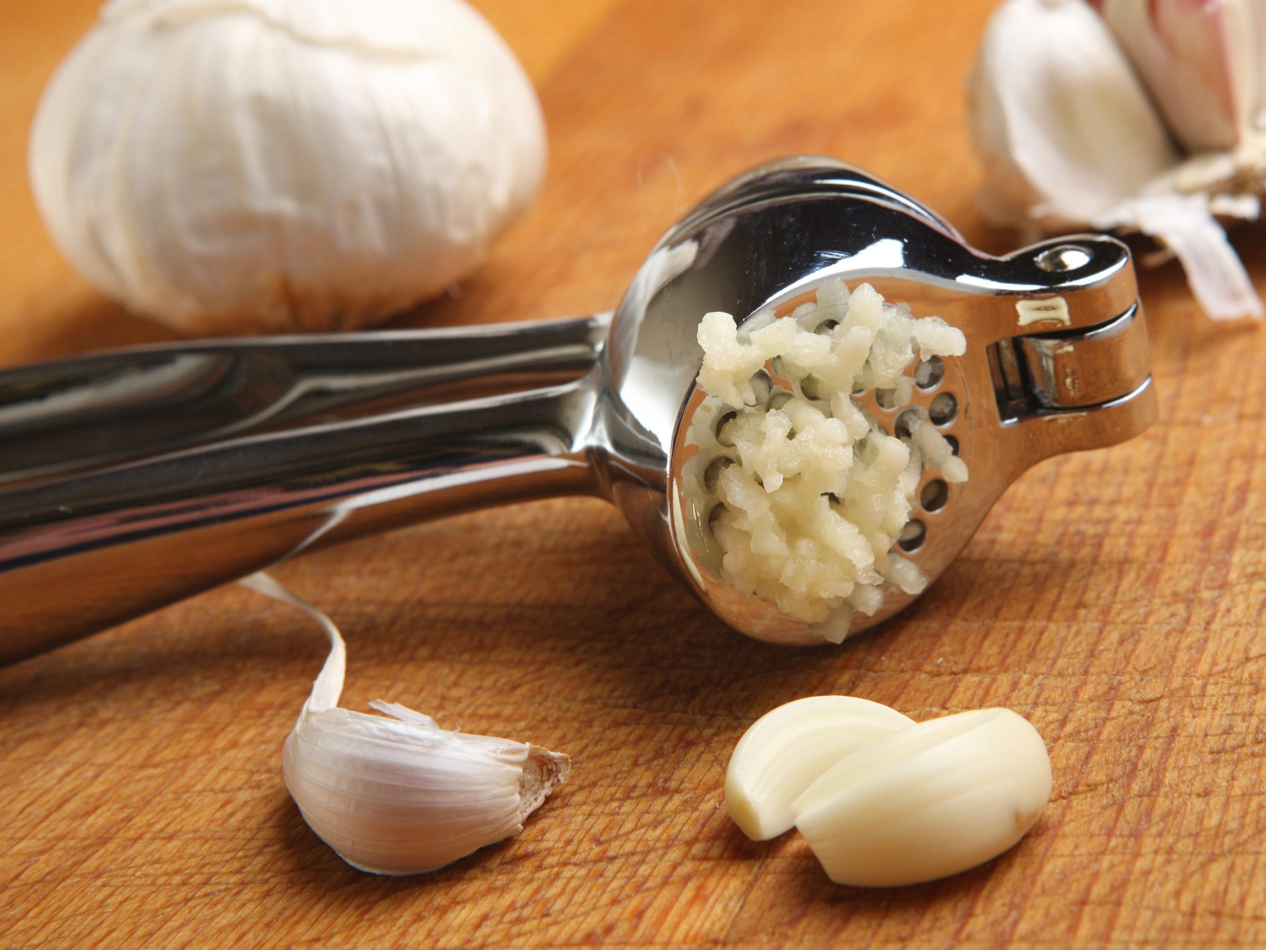A garlic press with crushed garlic coming out of the holes