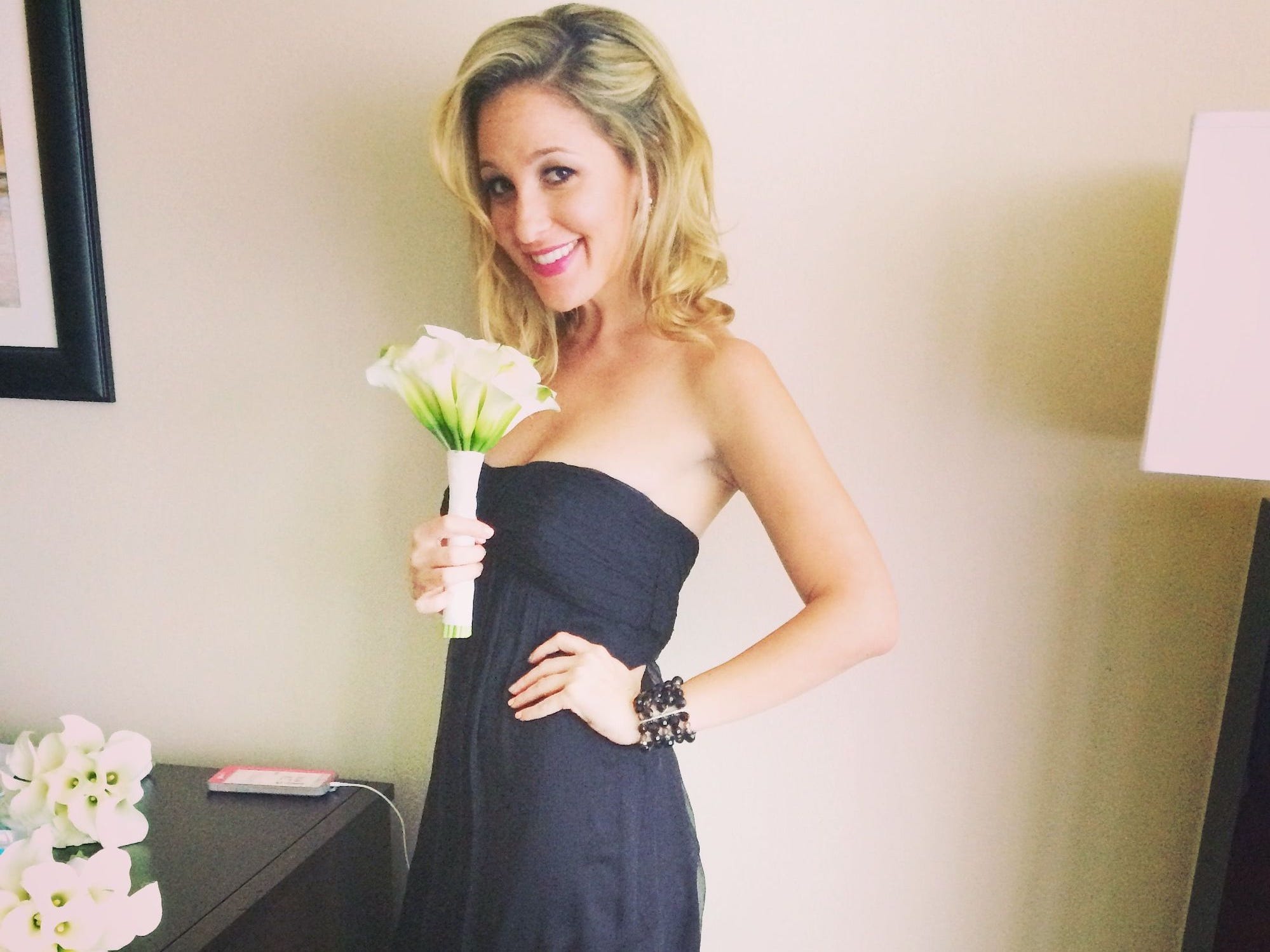 A bridesmaid poses for a photo holding a lily.