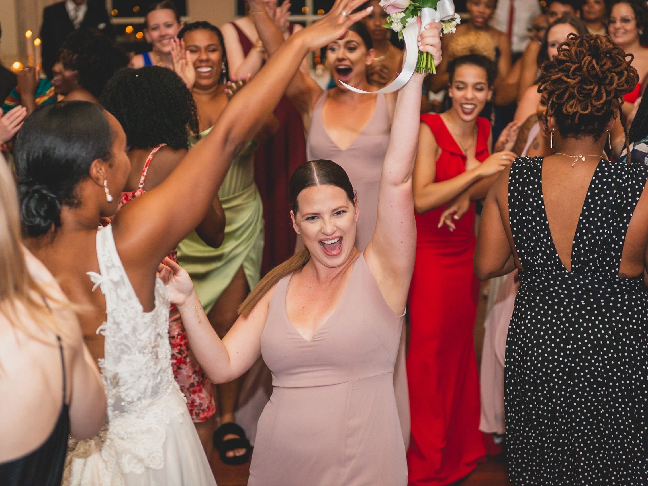 A bridesmaid holds up the bouquet she caught at a wedding.