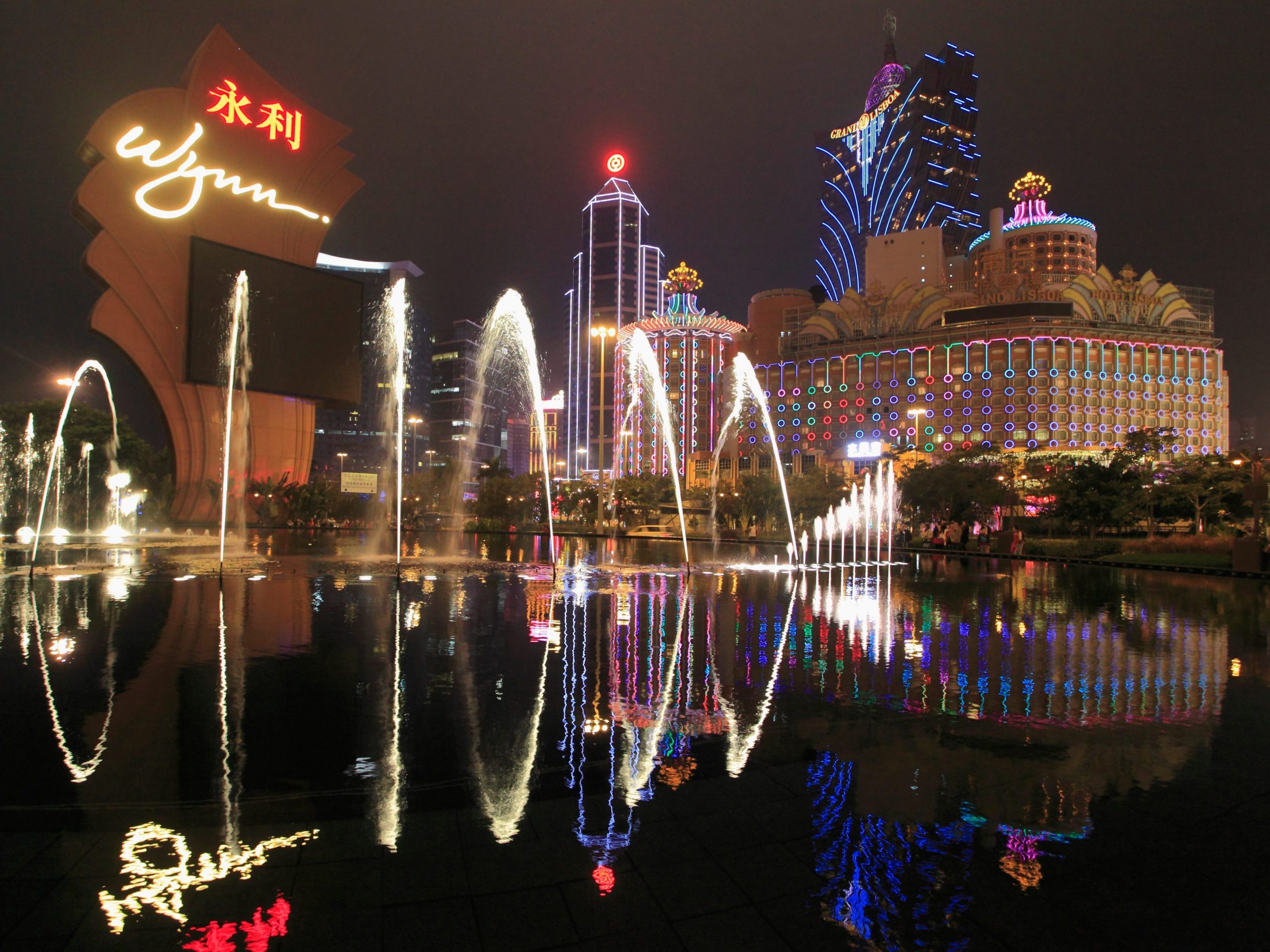 Macau at night with illuminated fountains and a Wynn resort in the background