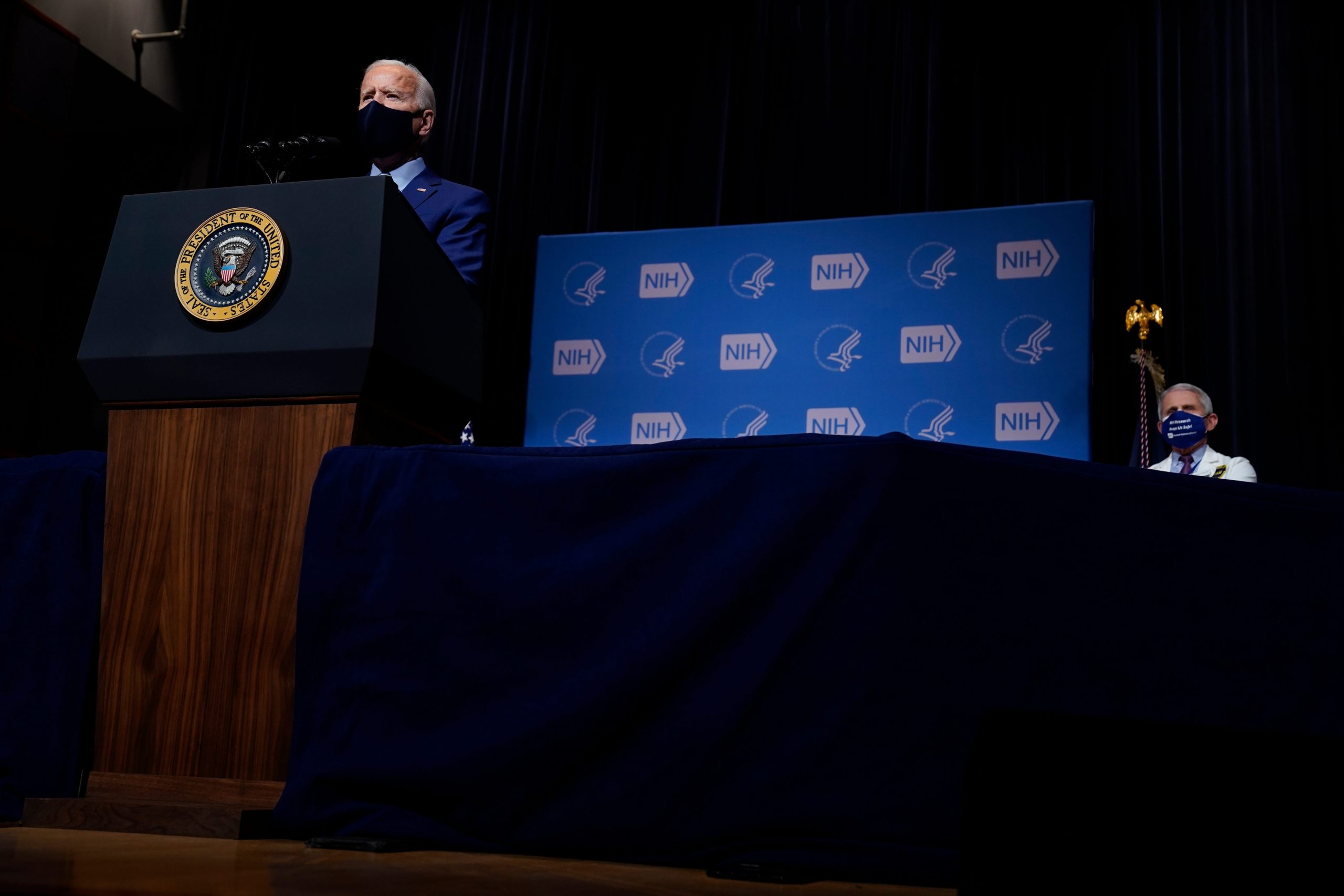 President Joe Biden speaks in front of NIH leader Dr. Anthony Fauci in a mask