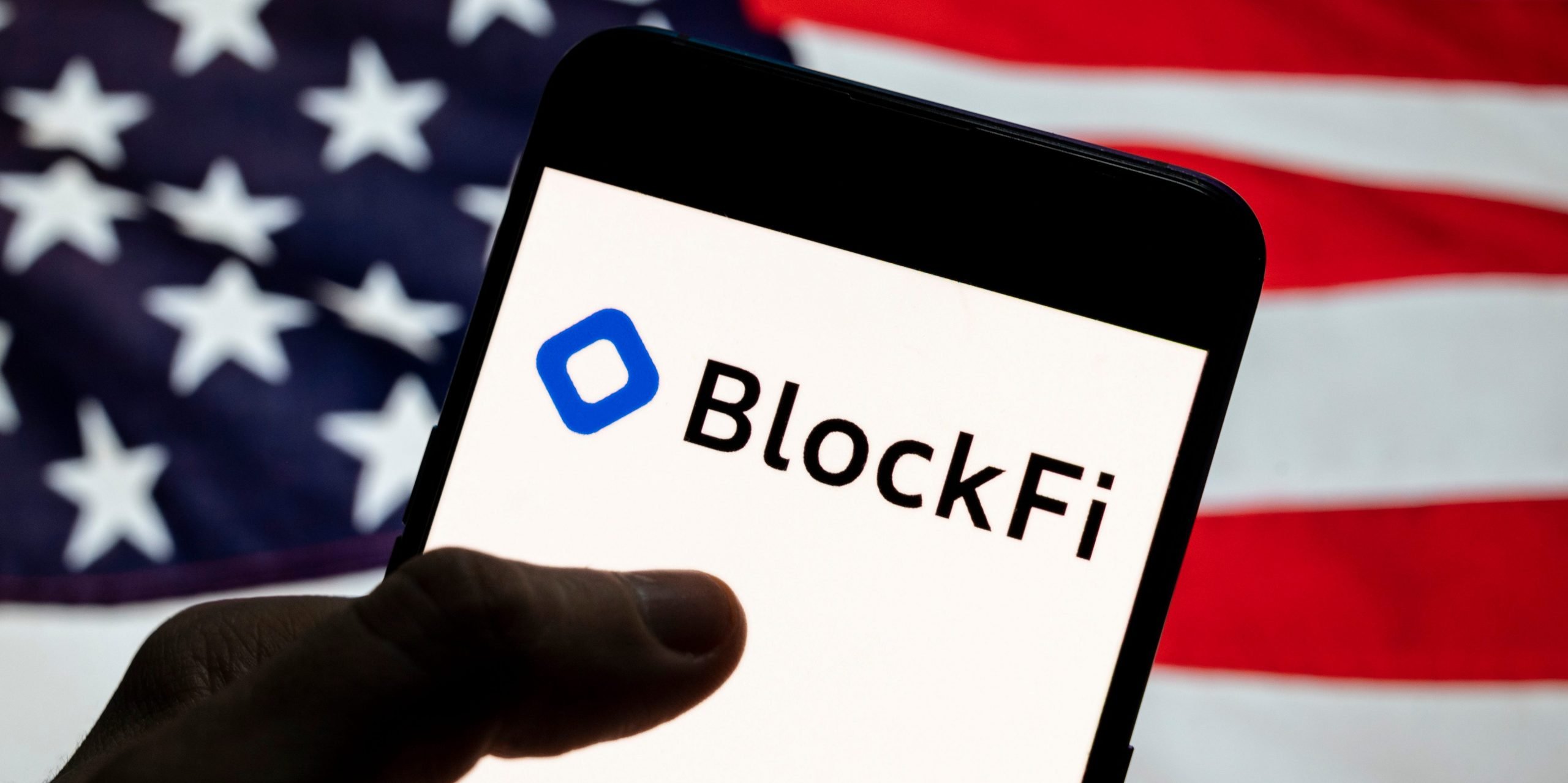 In this photo illustration the cryptocurrency exchange trading platform Blockfi logo seen displayed on a smartphone with a flag of the United States in the background.