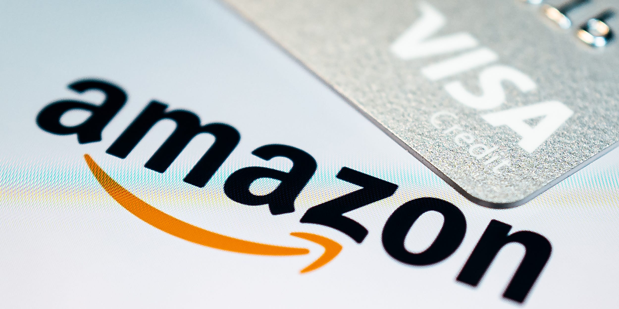 In this photo illustration, a Visa credit card is seen above the Amazon logo on the mobile app splash screen on November 17, 2021 in London, England.