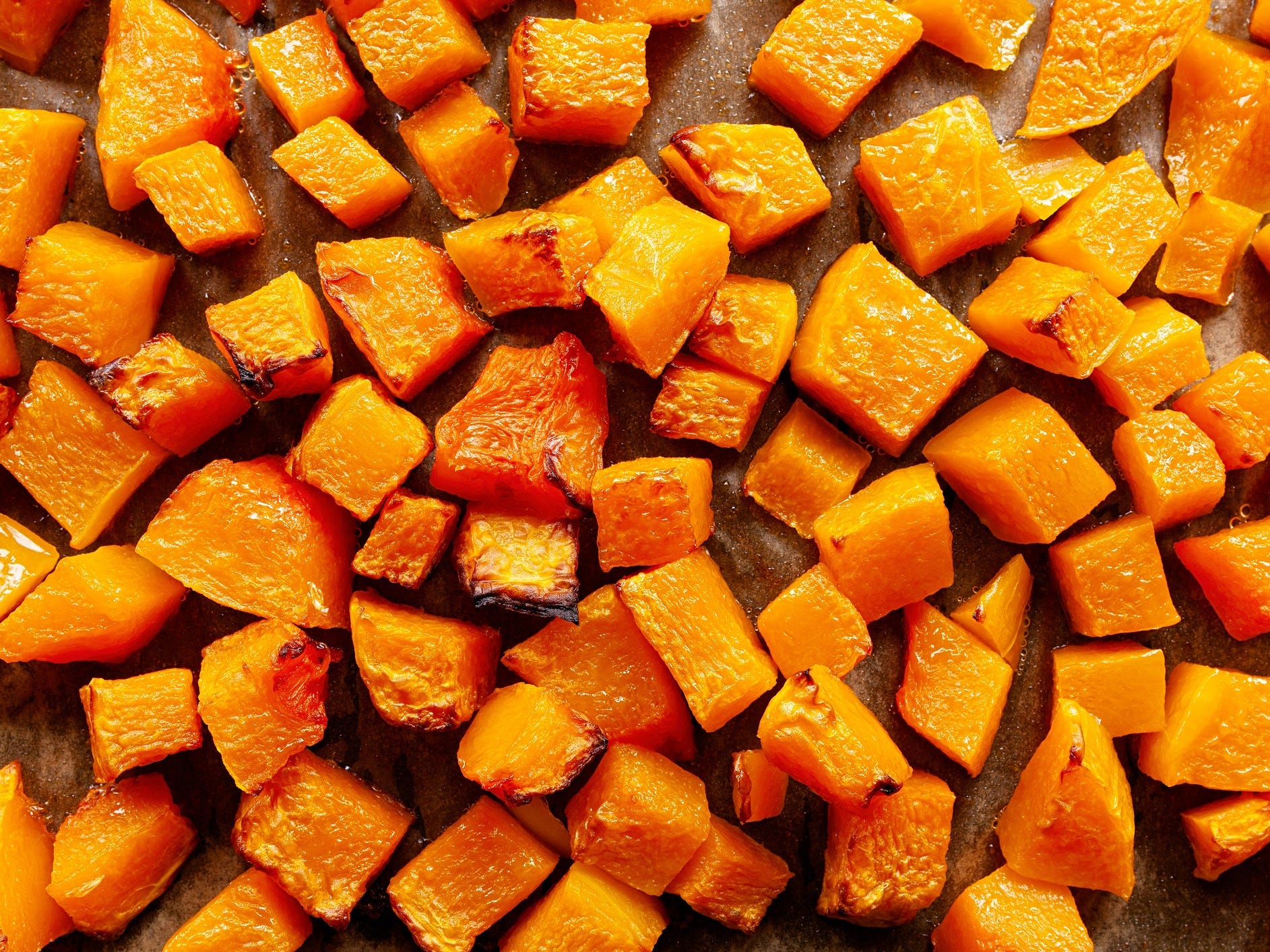 A top-down view of a tray of roasted butternut squash cubes