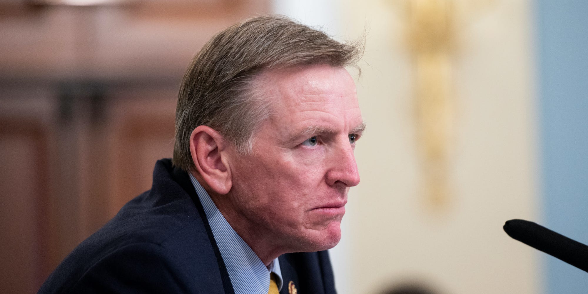 A side view of Rep Paul Gosar's head and shoulders, in front of a microphone.