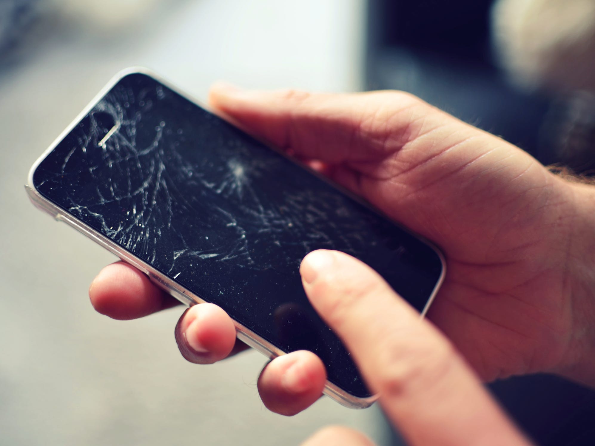 hands touching a smartphone with a broken cracked screen