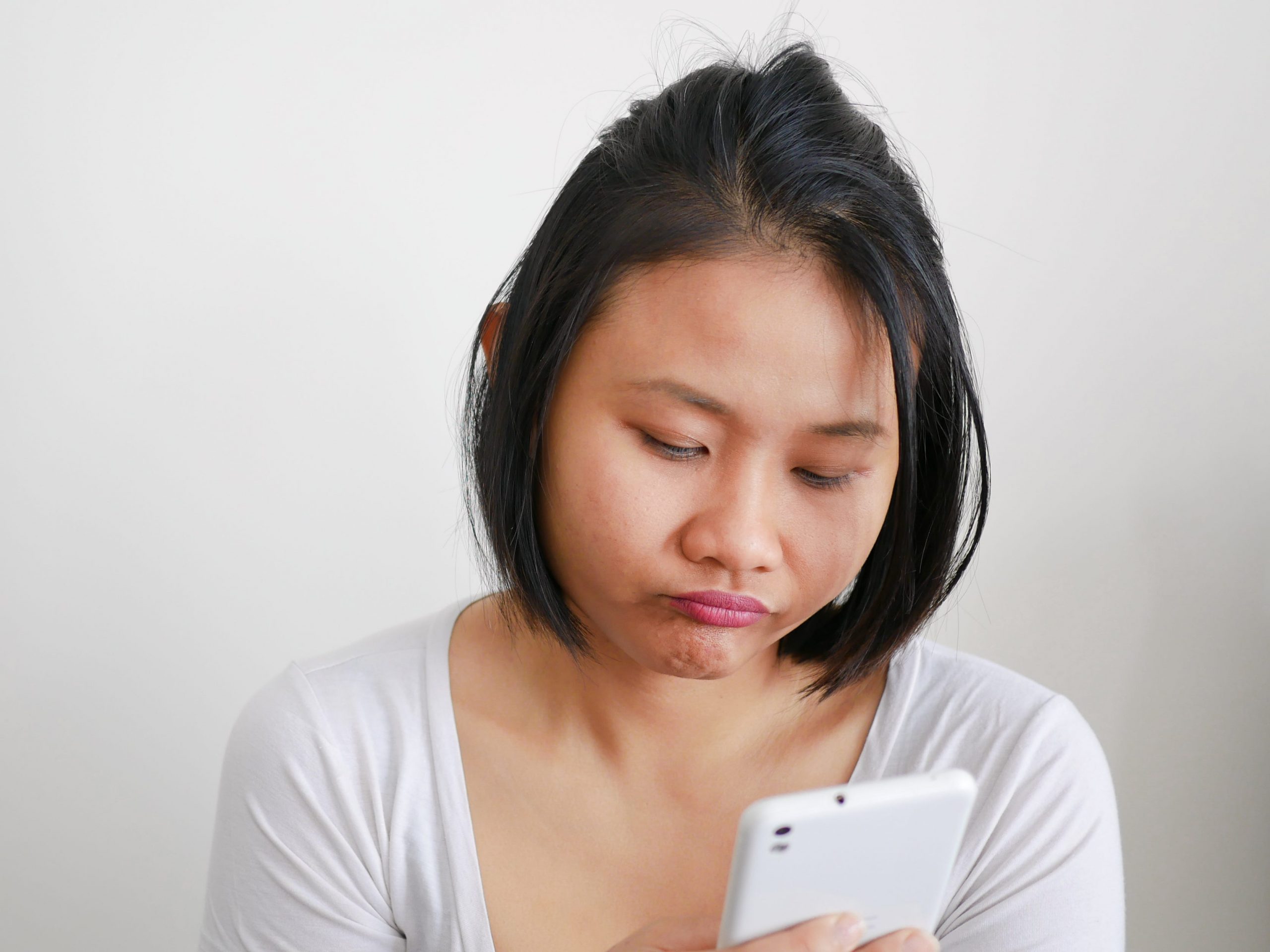 Woman looking down at her phone, waiting.