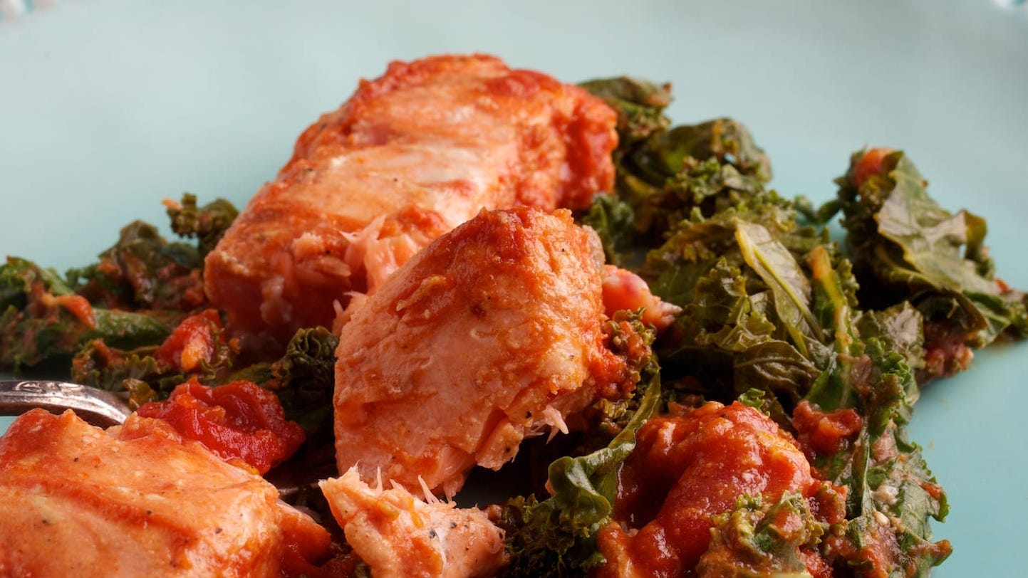 A salmon with kale dish on a blue plate.