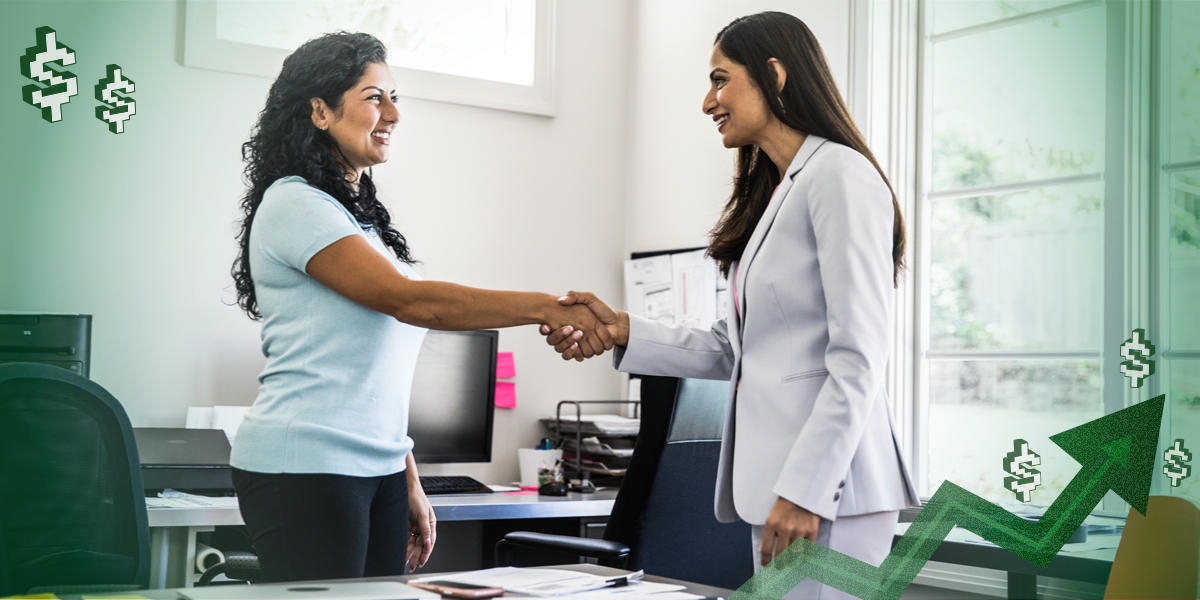 Two women in a meeting shaking hands.