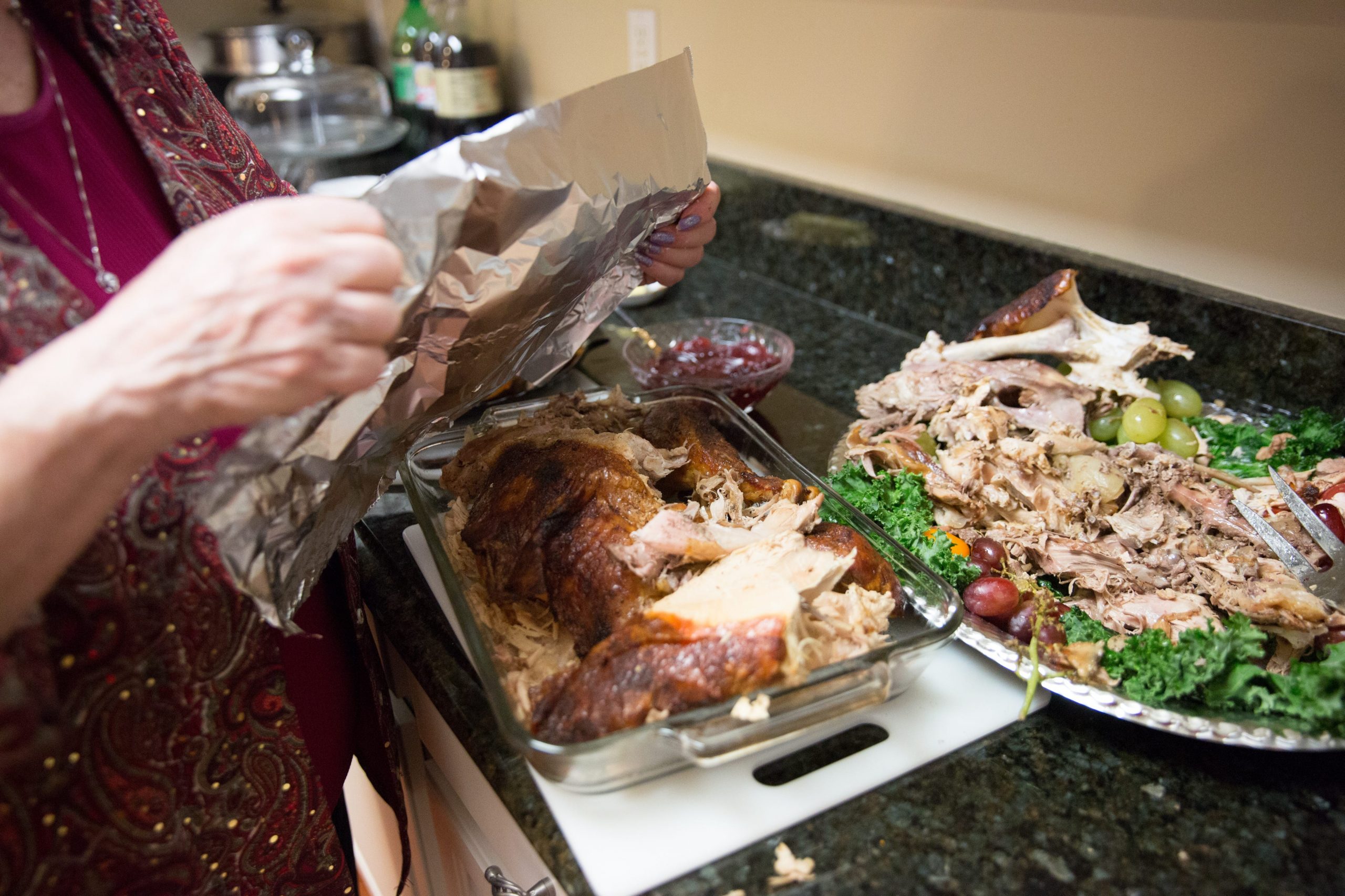 woman puts foil on thanksgiving leftovers