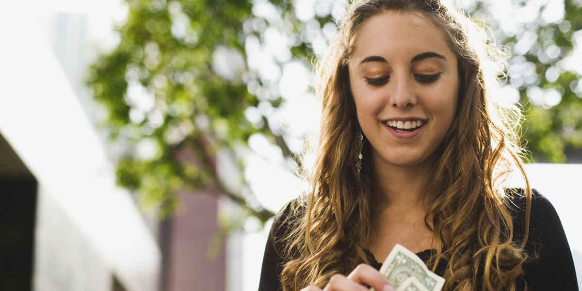 A photo of a young woman looking at money.